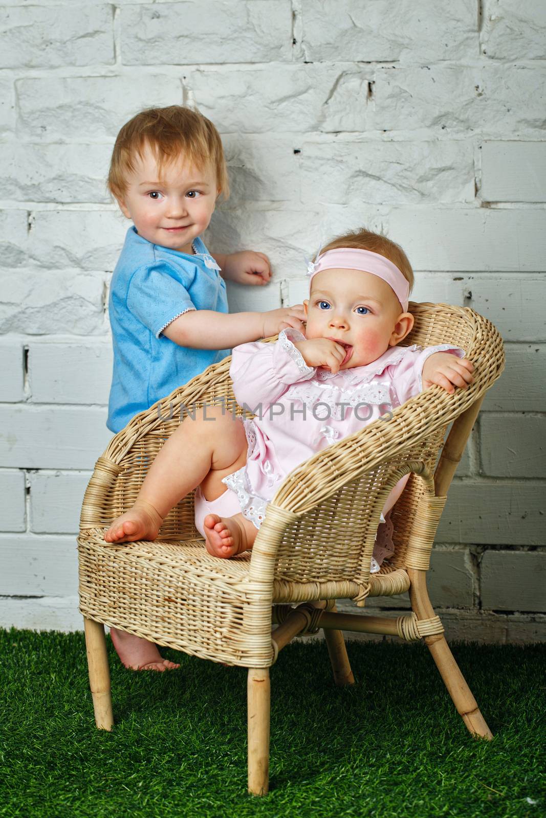 Brother and sister playing in the backyard next to the wicker chair