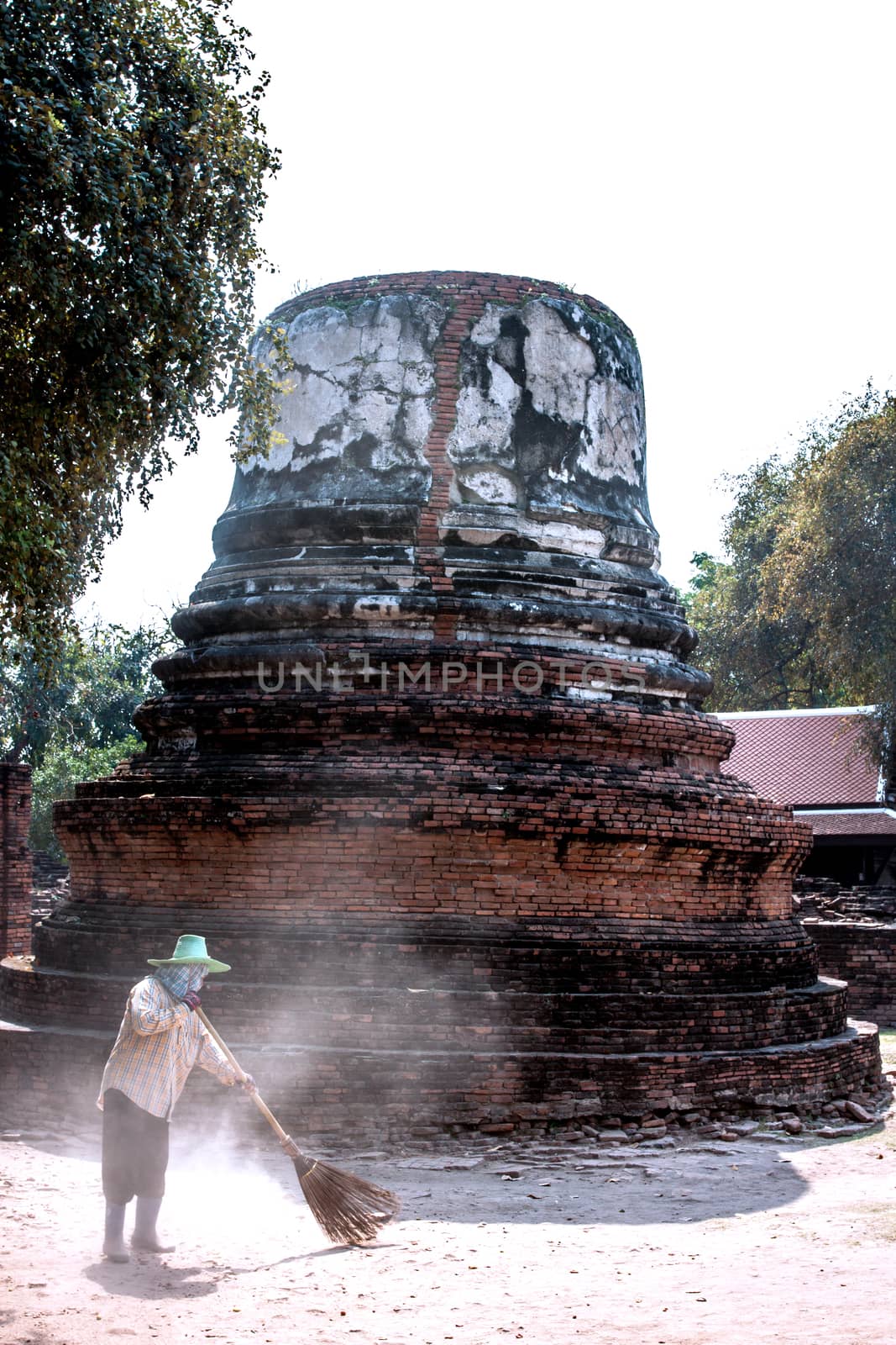 worker sweeper cleaning around ancient pagoda with broom tool by kannapon