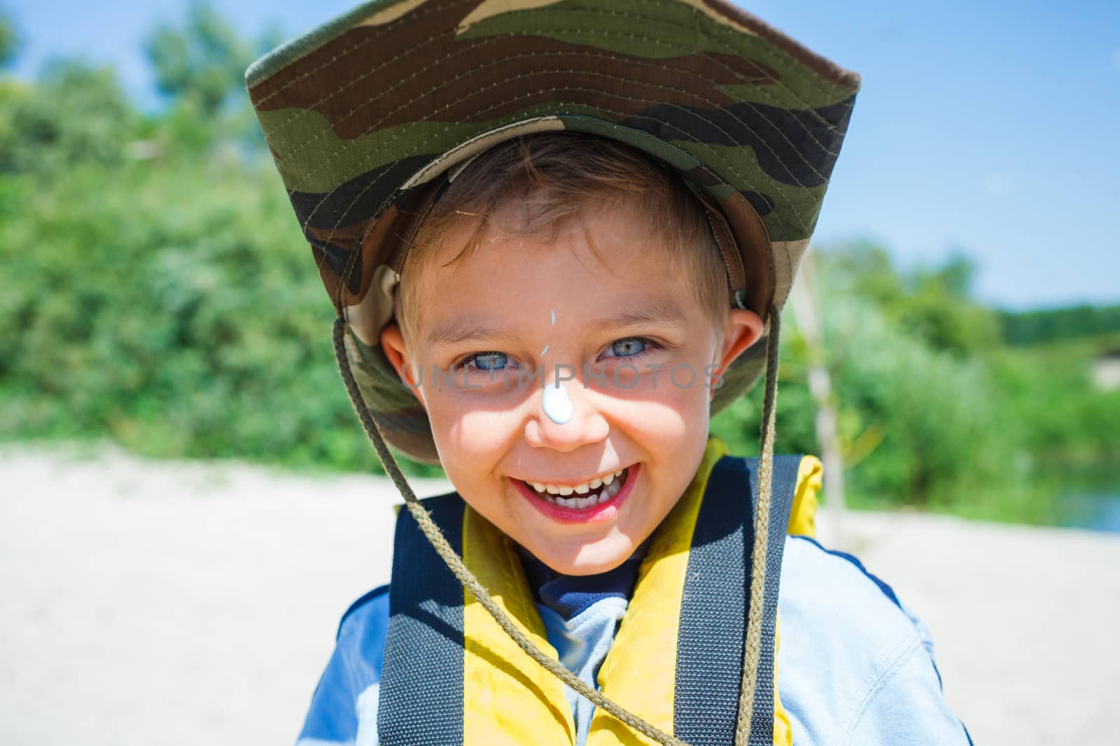 Ready kayaking. Portrait of happy little boy near the river and enjoying a lovely summer day