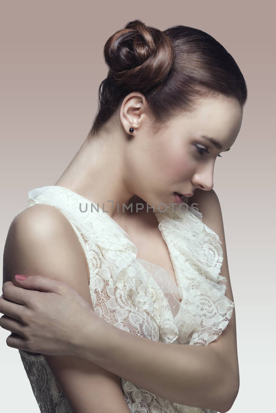 porttrait of pretty brunette girl with elegant creative hair-style in romantic pose wearing white lace shirt