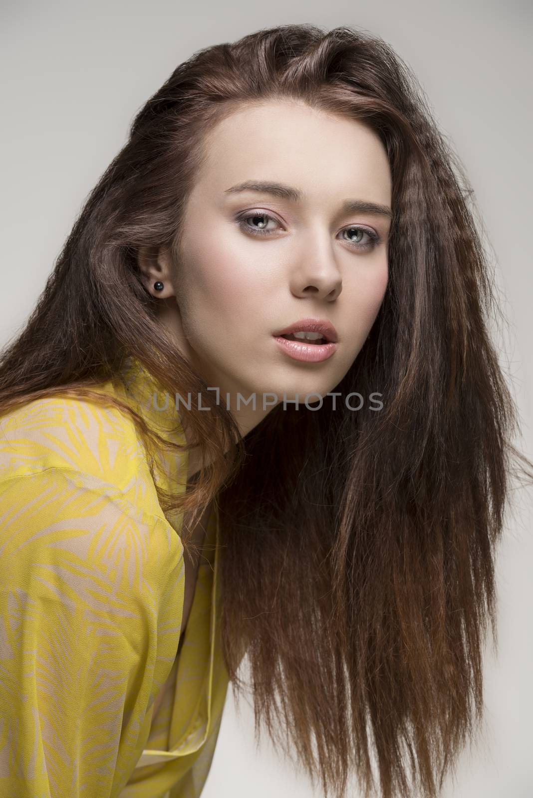 portrait of sensual female with long brown hair and sexy yellow transparent nightgown looking in camera