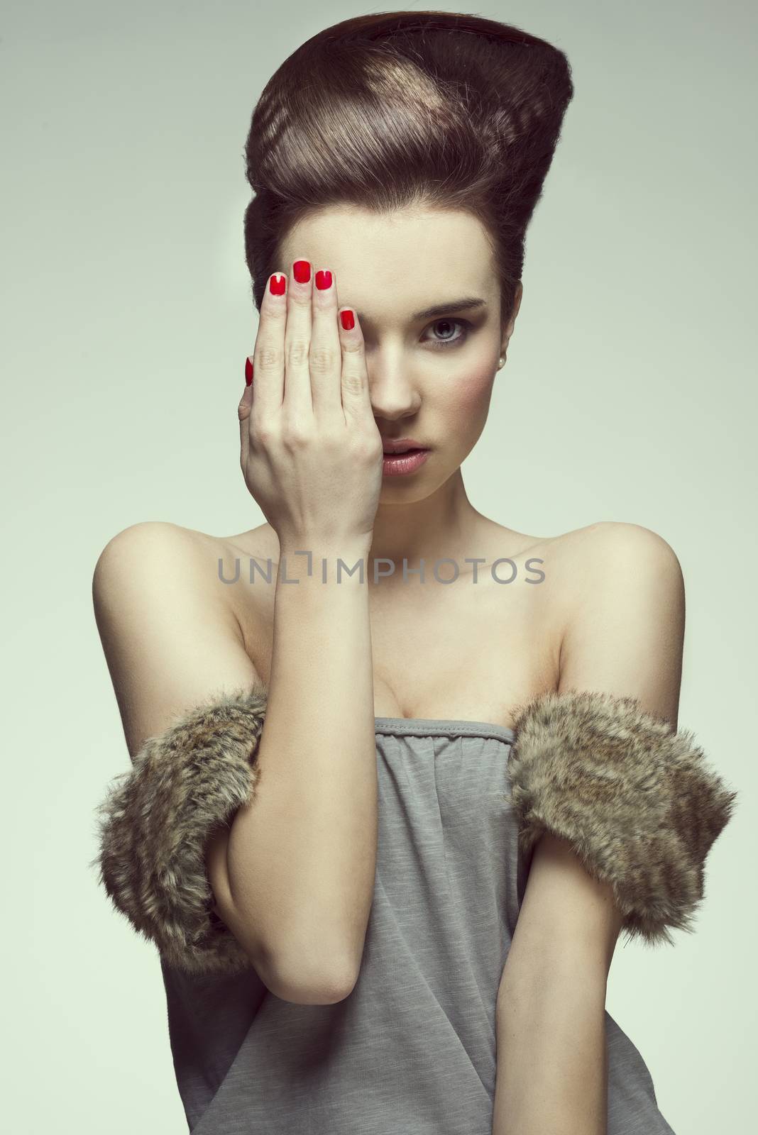 pretty and sexy young girl with creative hairstyle looking in camera and covering one eyes with hand