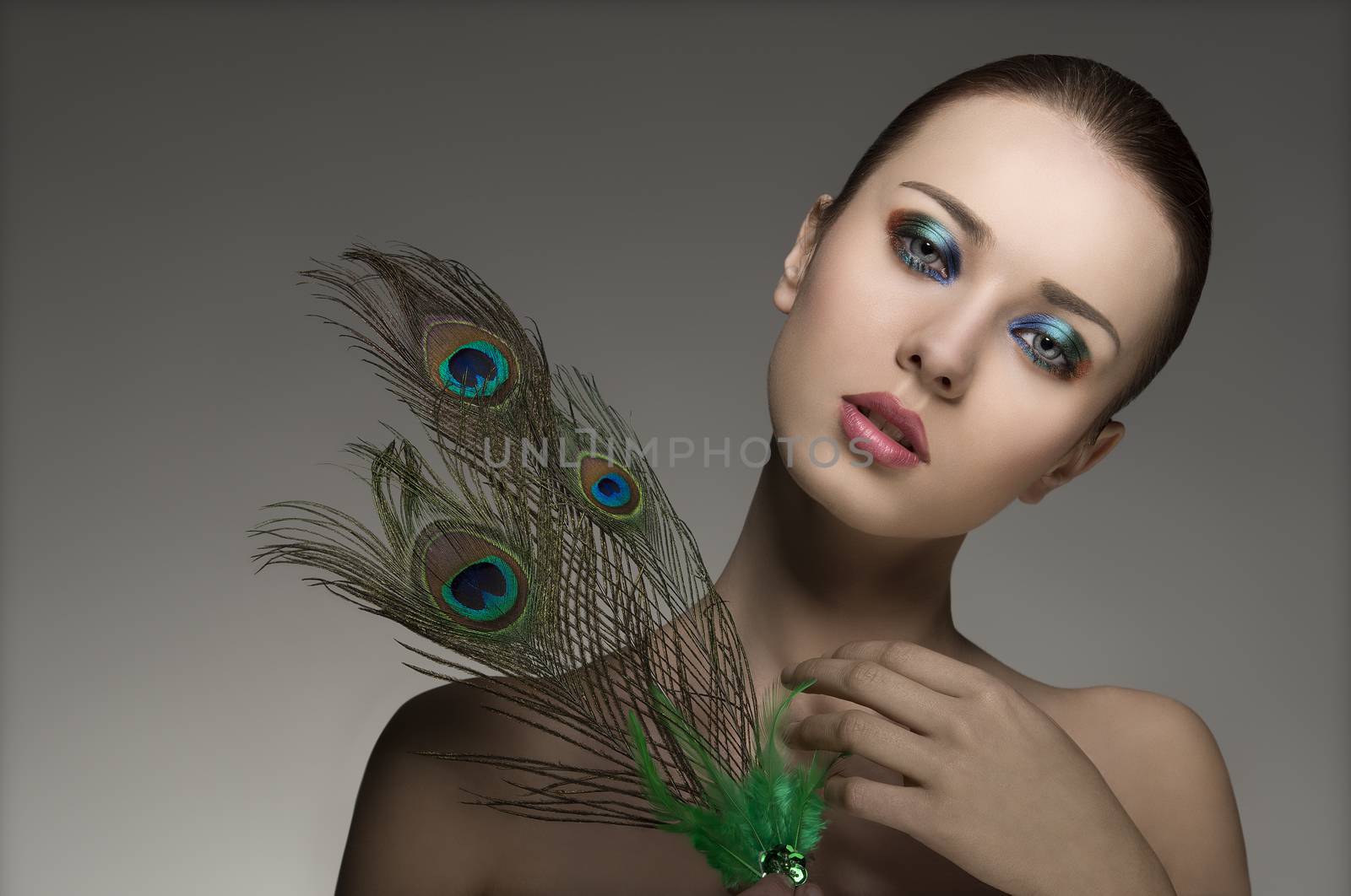 amazing portrait of young girl with perfect skin, naked shoulders, make-up and accessory inspired by peacock���s feathers