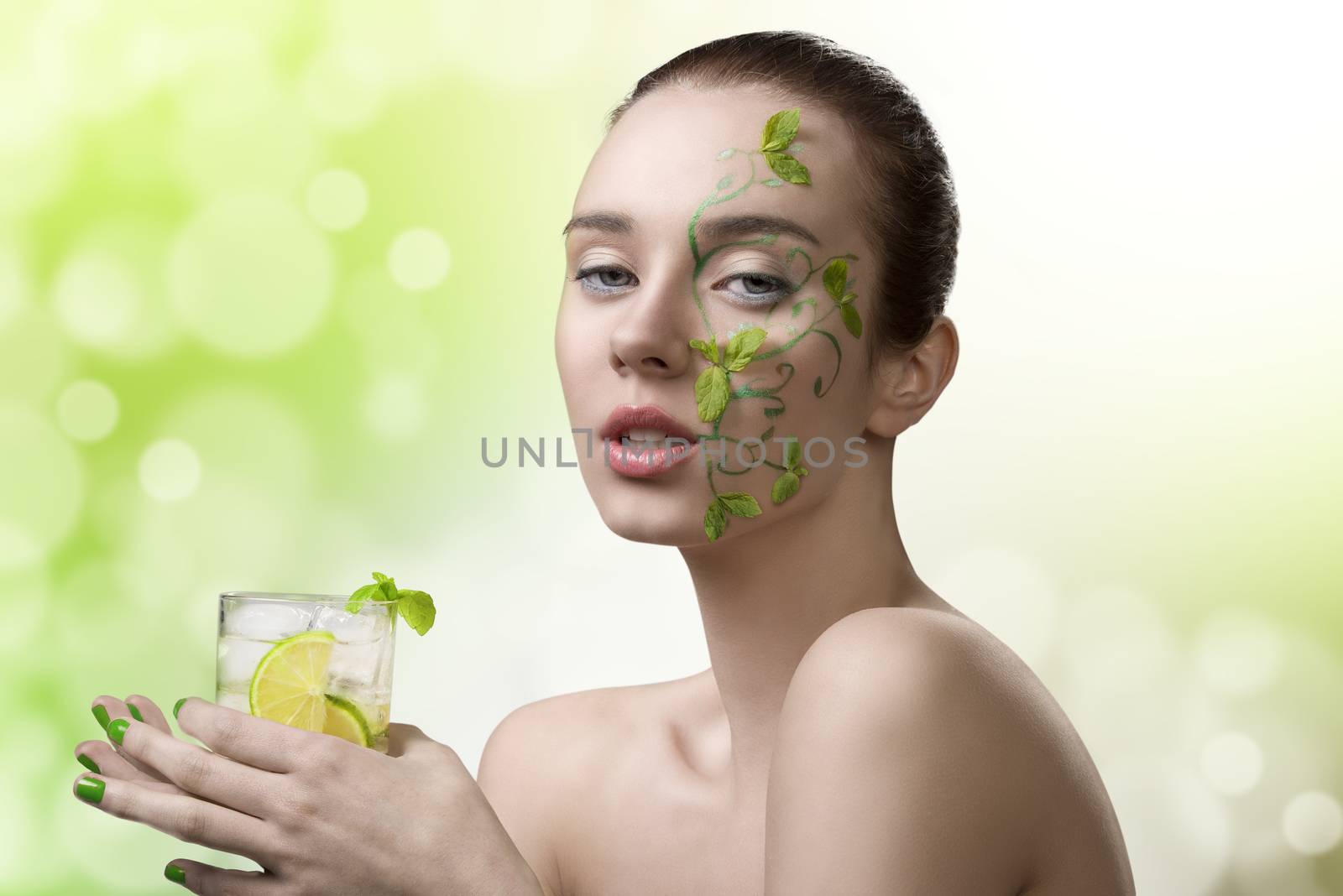 sensual woman with naked shoulders, creative fresh make-up with mint leaves and cold mojito cocktail in the hand