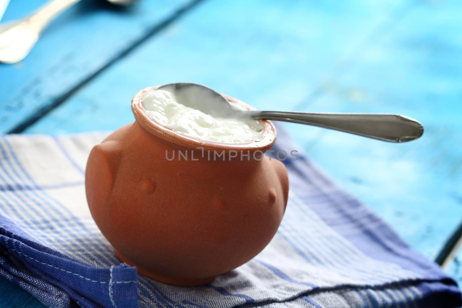 Homemade yogurt in a ceramic pot and spoon