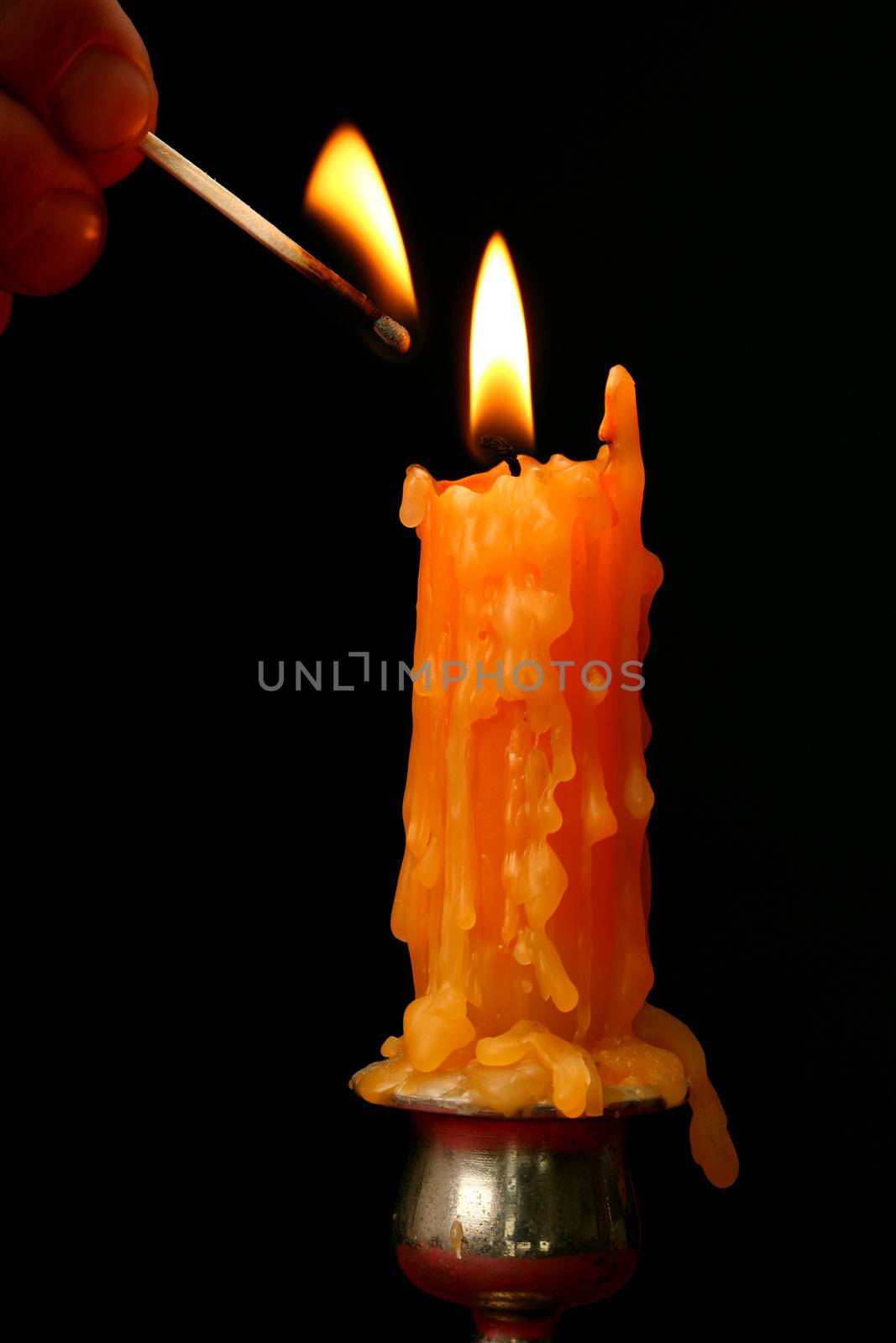 Hand lighting a candle with match stick