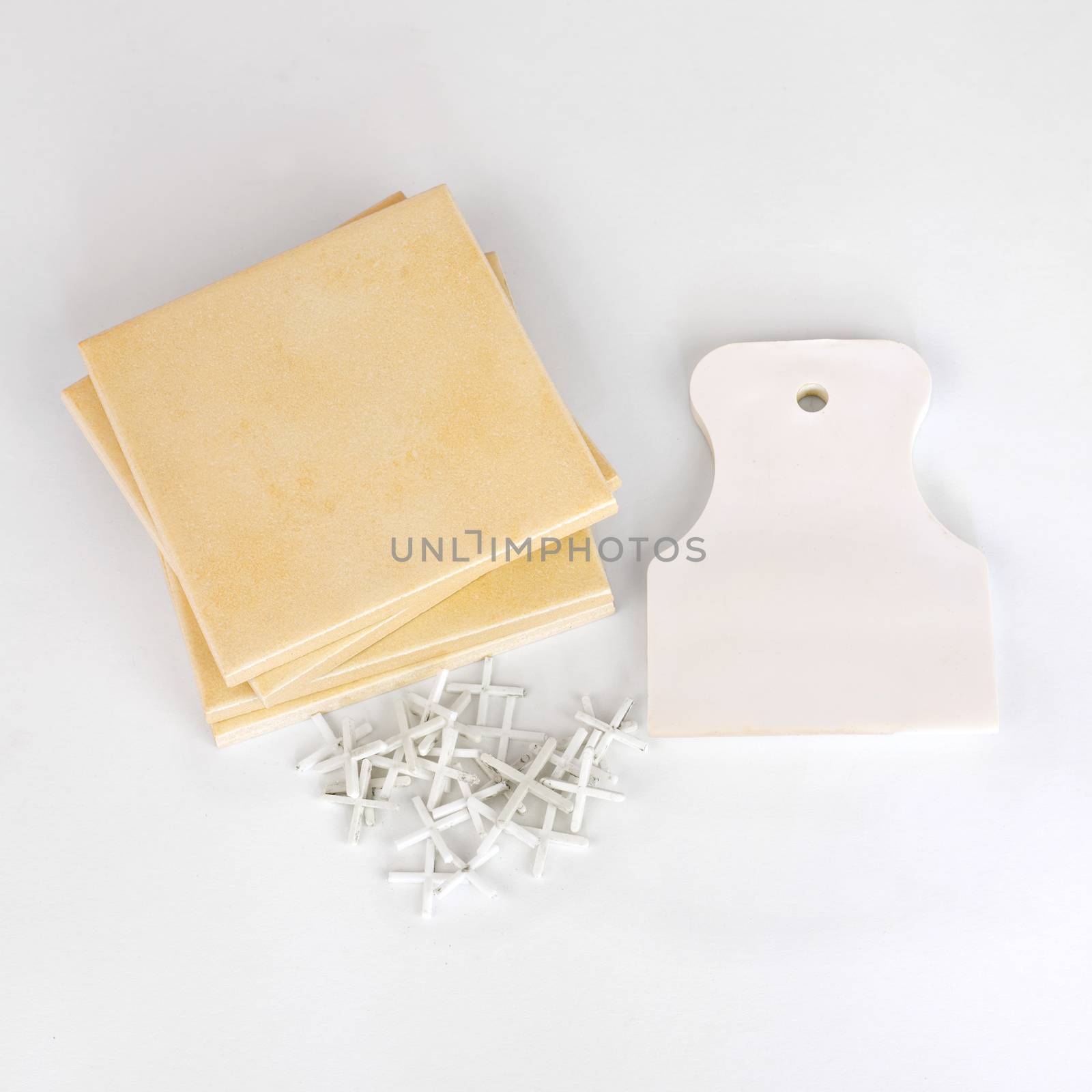 Stack of ceramic tiles and tools on a white background