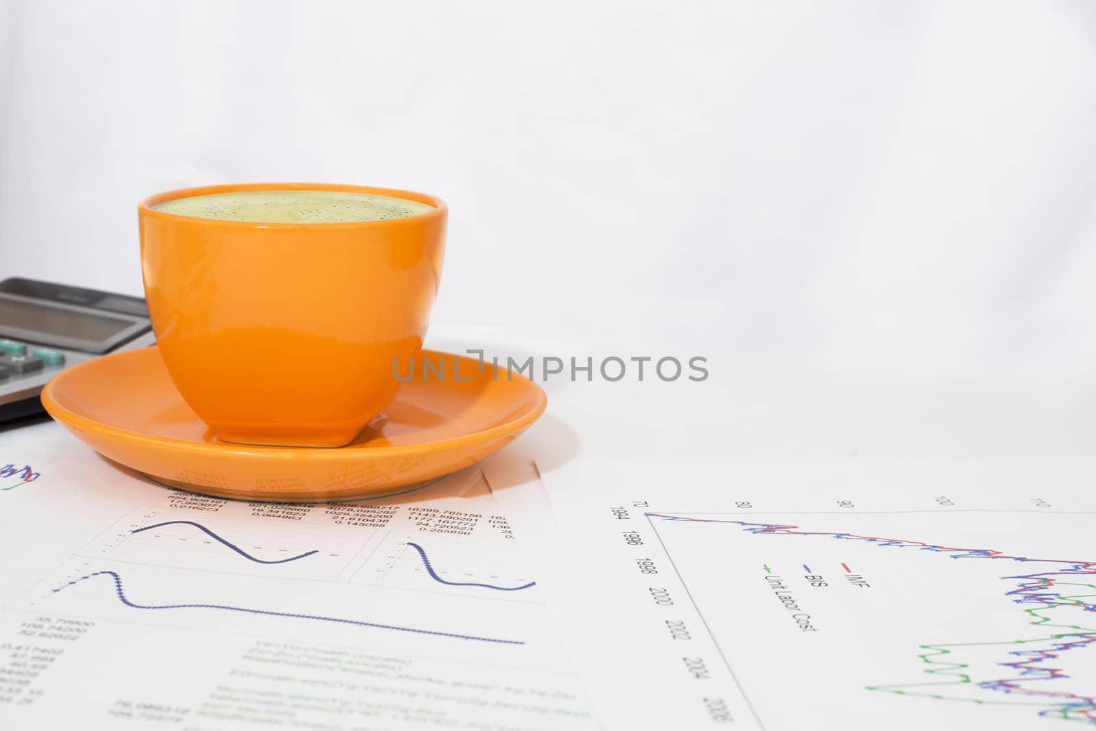 Cup of coffee, calculator and paper with graphs by cherezoff