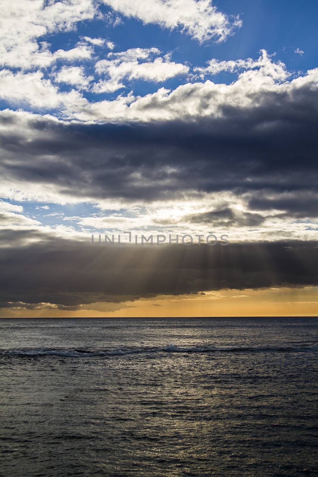 sun ray beaming from behind clouds over the pacific ocean