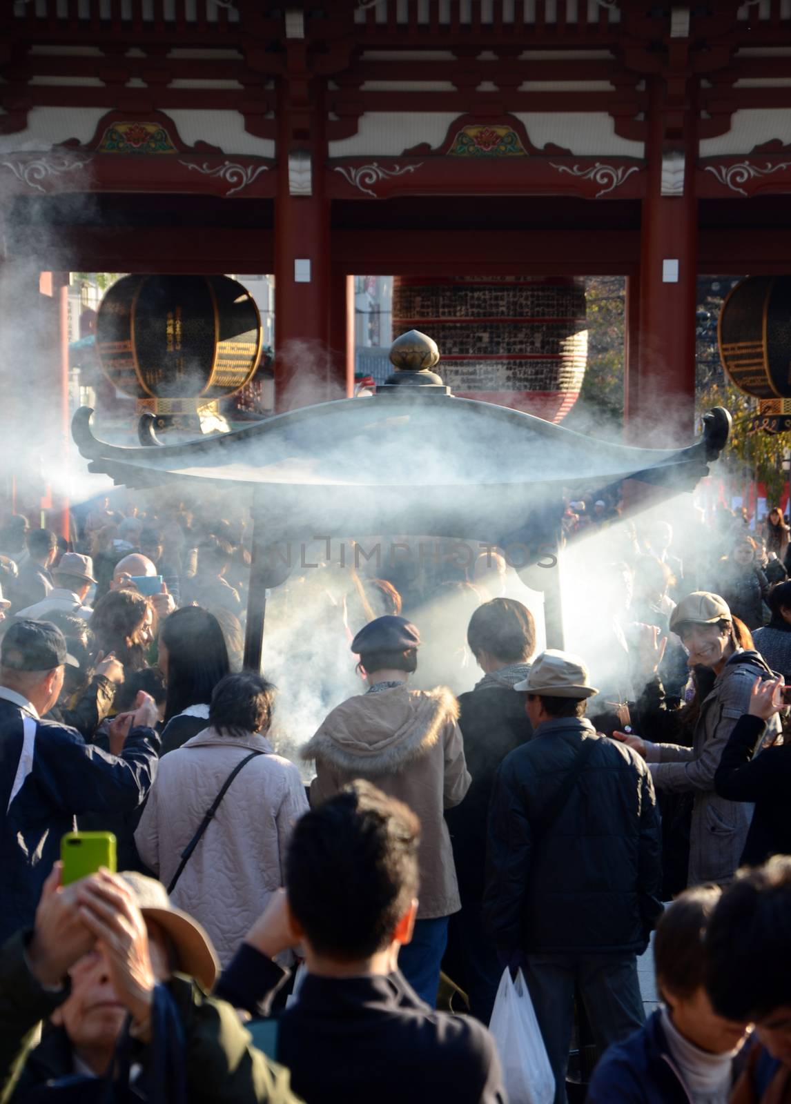TOKYO, JAPAN - NOV 21: Buddhists gather around a fire to light incense and pray at Sensoji Temple on November 21, 2013 in Tokyo, Japan.