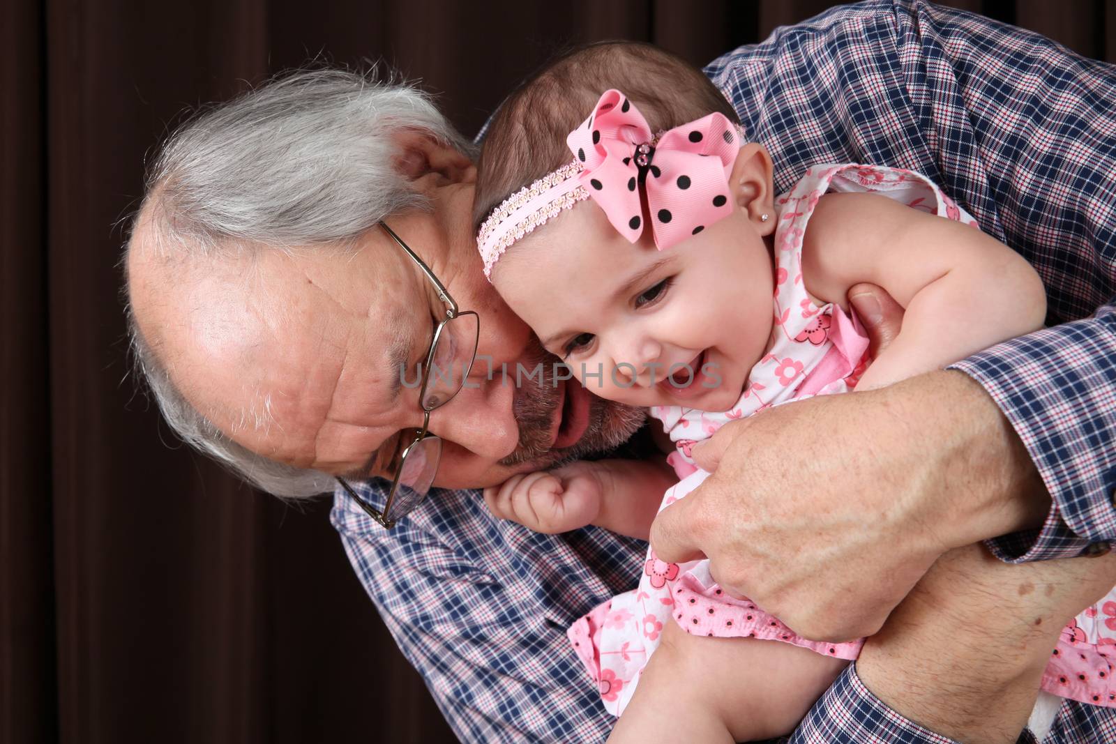 Grandfather cuddling his granddaughter against brown background