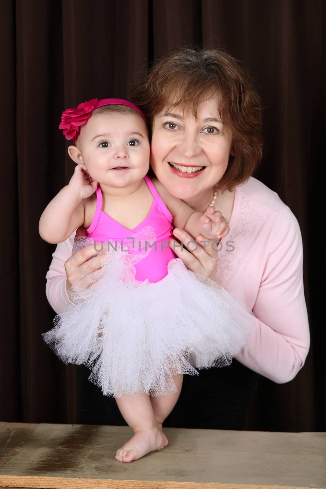 Grandmother and ballerina baby portrait against brown