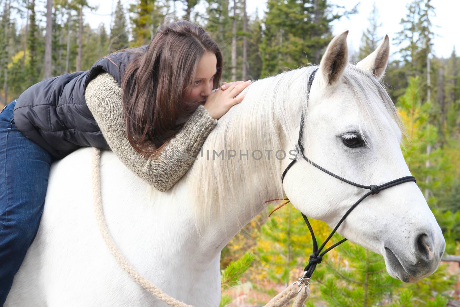 Beautiful brunette female spending time with her white horse