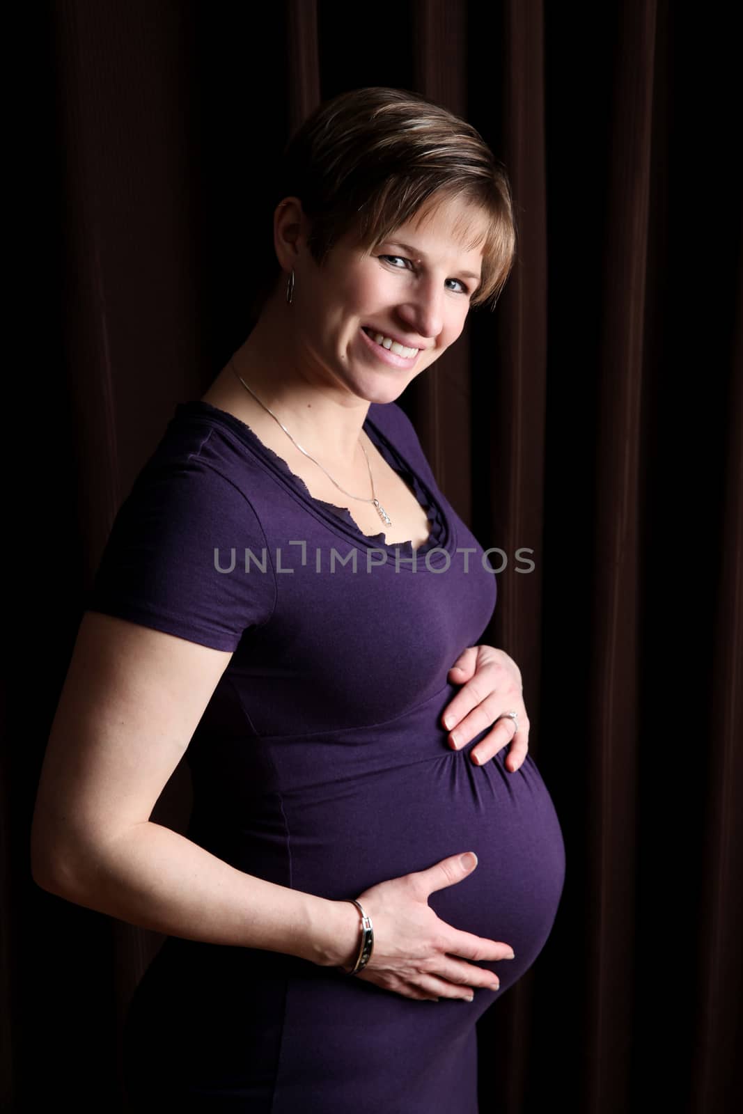 Pregnant woman against dark background with uneven lighting
