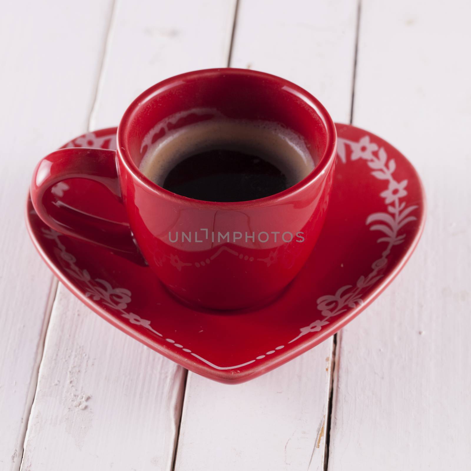 Coffee in a red cup over white wood