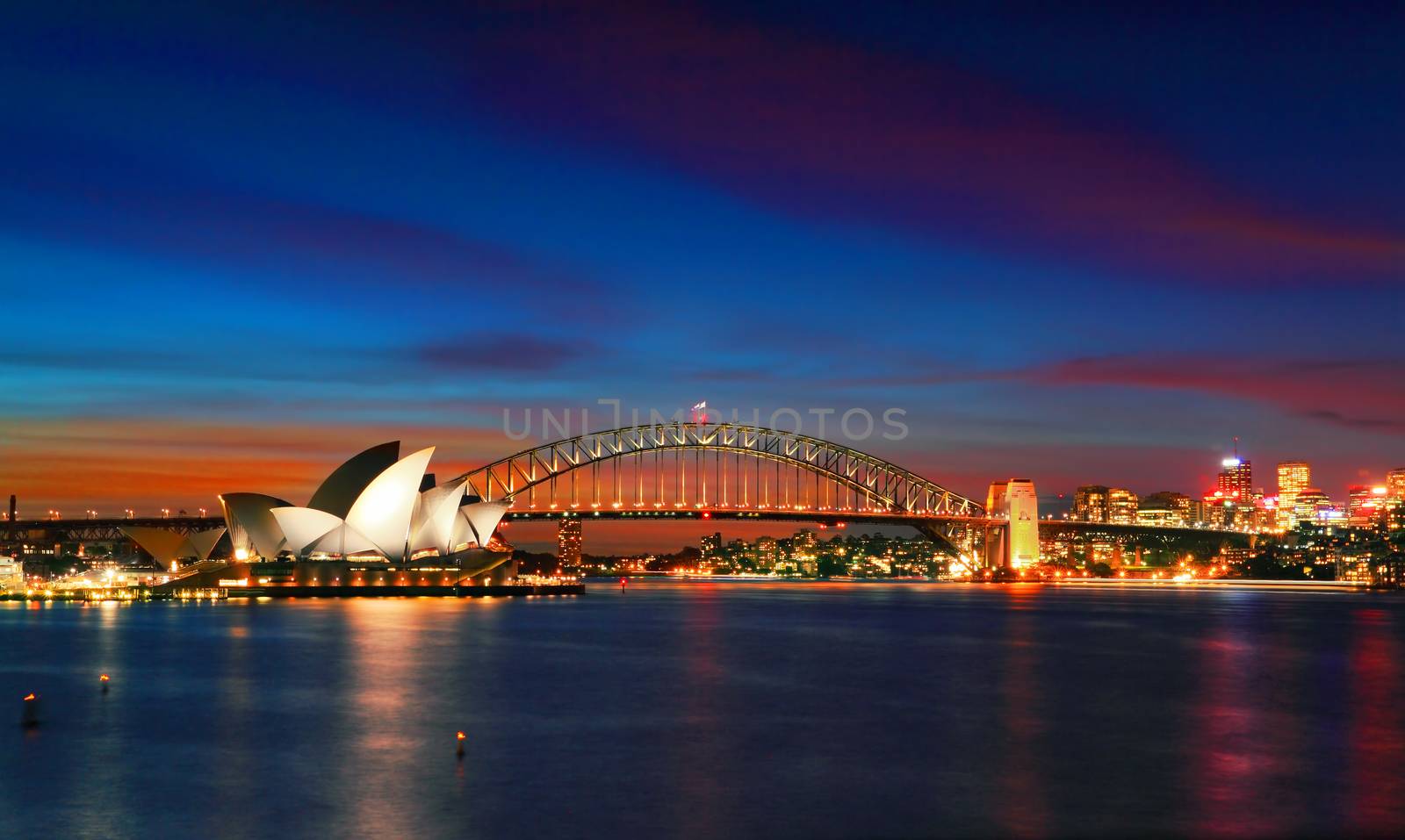 SYDNEY, AUSTRALIA - APRIL 8, 2014; Two of Sydney's famous icons, the Sydney Opera House and Sydney Harbour Bridge lit up at dusk after a vivid sunset, the sky still aglow with colour.   Look closely and you can see bridge climbers on the bridge.   Long exposure