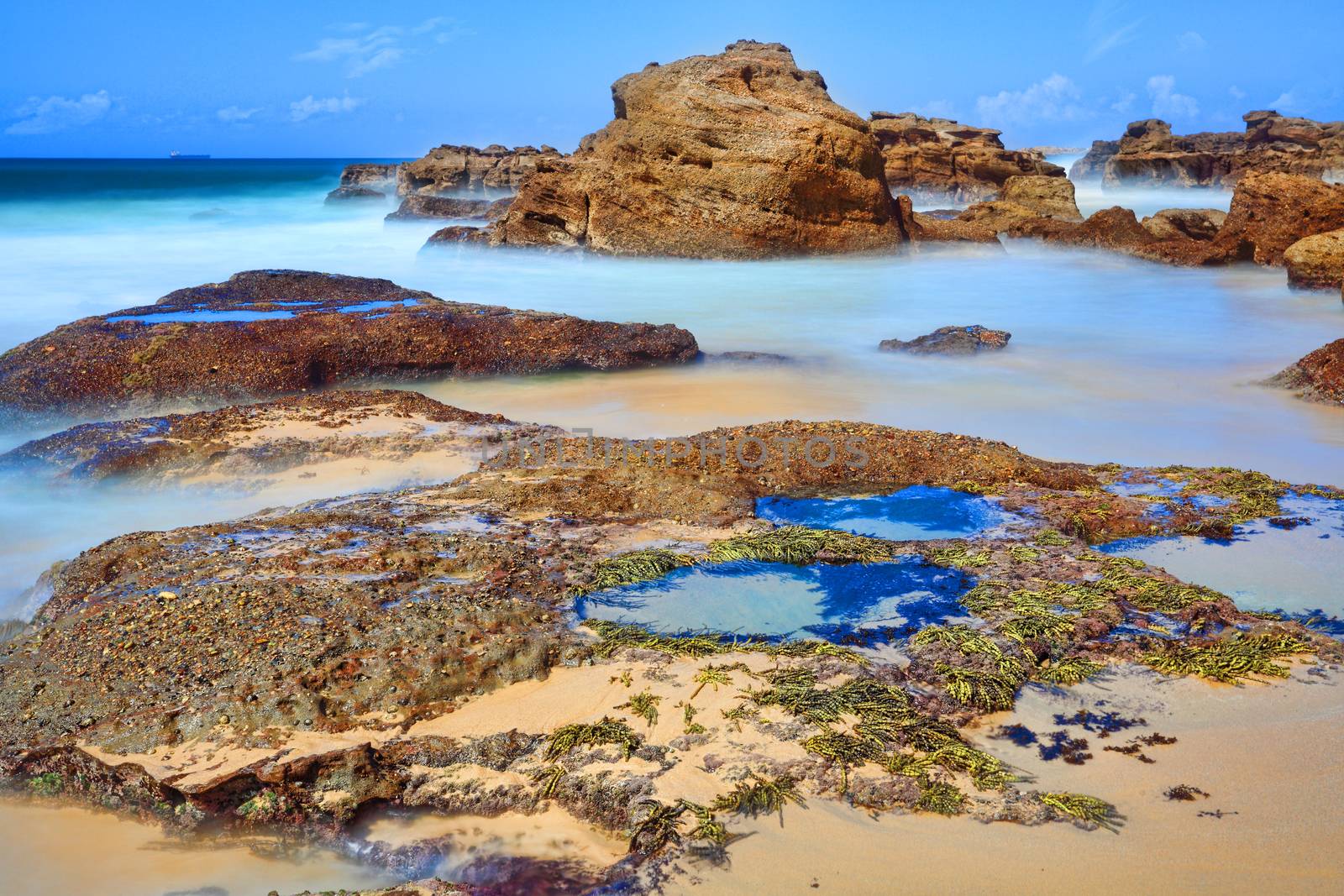 Long exposure of rocks and rock pools at low tide, motion in the water.