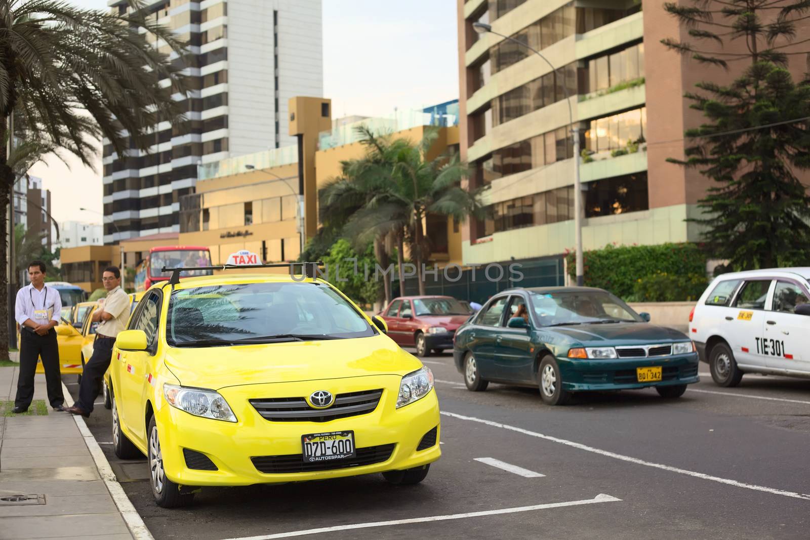 LIMA, PERU - MARCH 16, 2012: Unidentified taxi drivers standing next to yellow cabs on the Malecon de la Reserva at Larcomar waiting for passengers on March 16, 2012 in Miraflores, Lima, Peru. There are many taxis in Lima, and they are used very frequently by the people. 