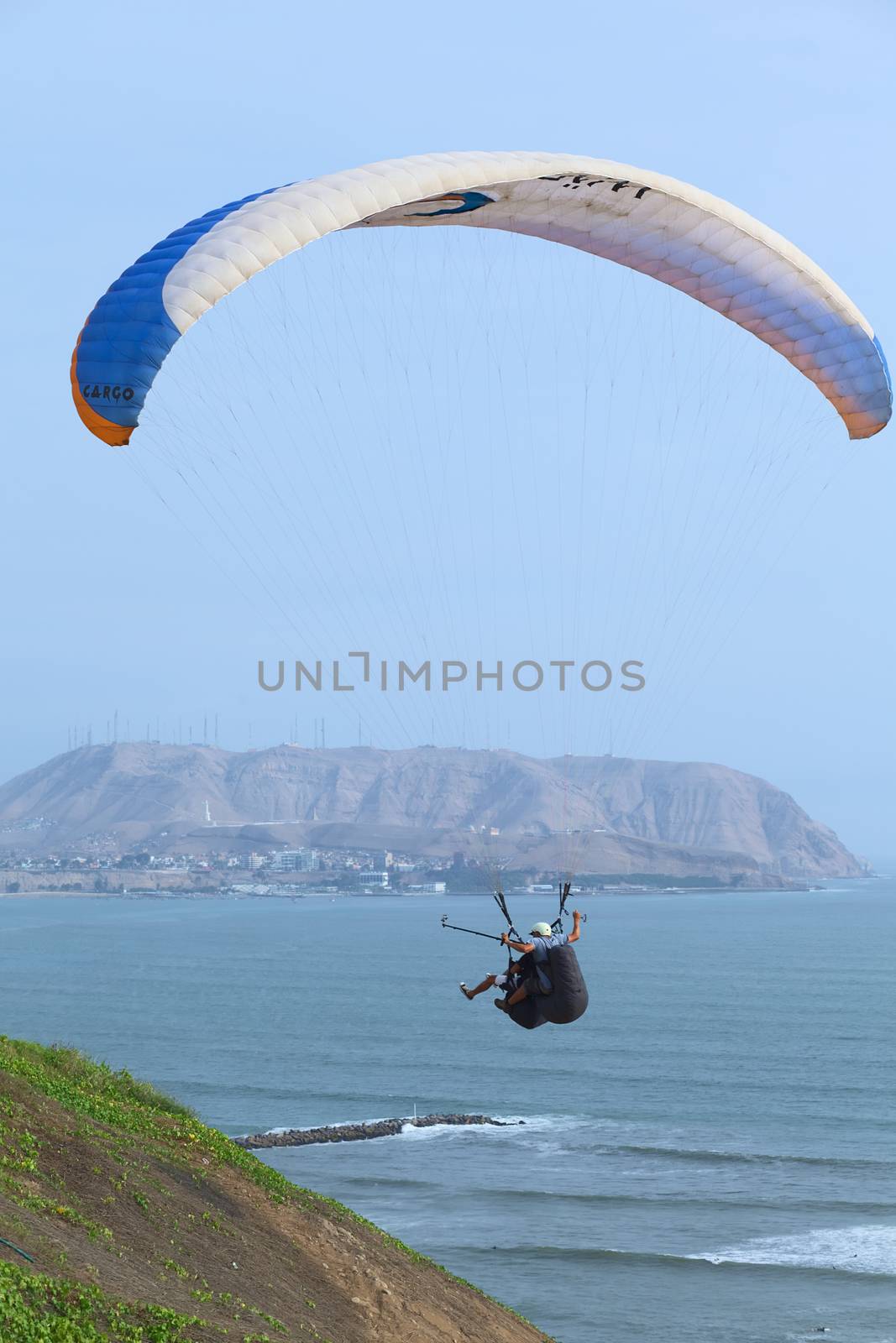 LIMA, PERU - MARCH 19, 2012: Unidentified people in paragliding tandem flight at the coast of Miraflores with view onto Chorrillos in the back on March 19, 2012 in Lima, Peru. Paragliding is a popular sport on the coast of Miraflores, where winds are usually good and in good weather a big part of the coast of Lima can be seen. 