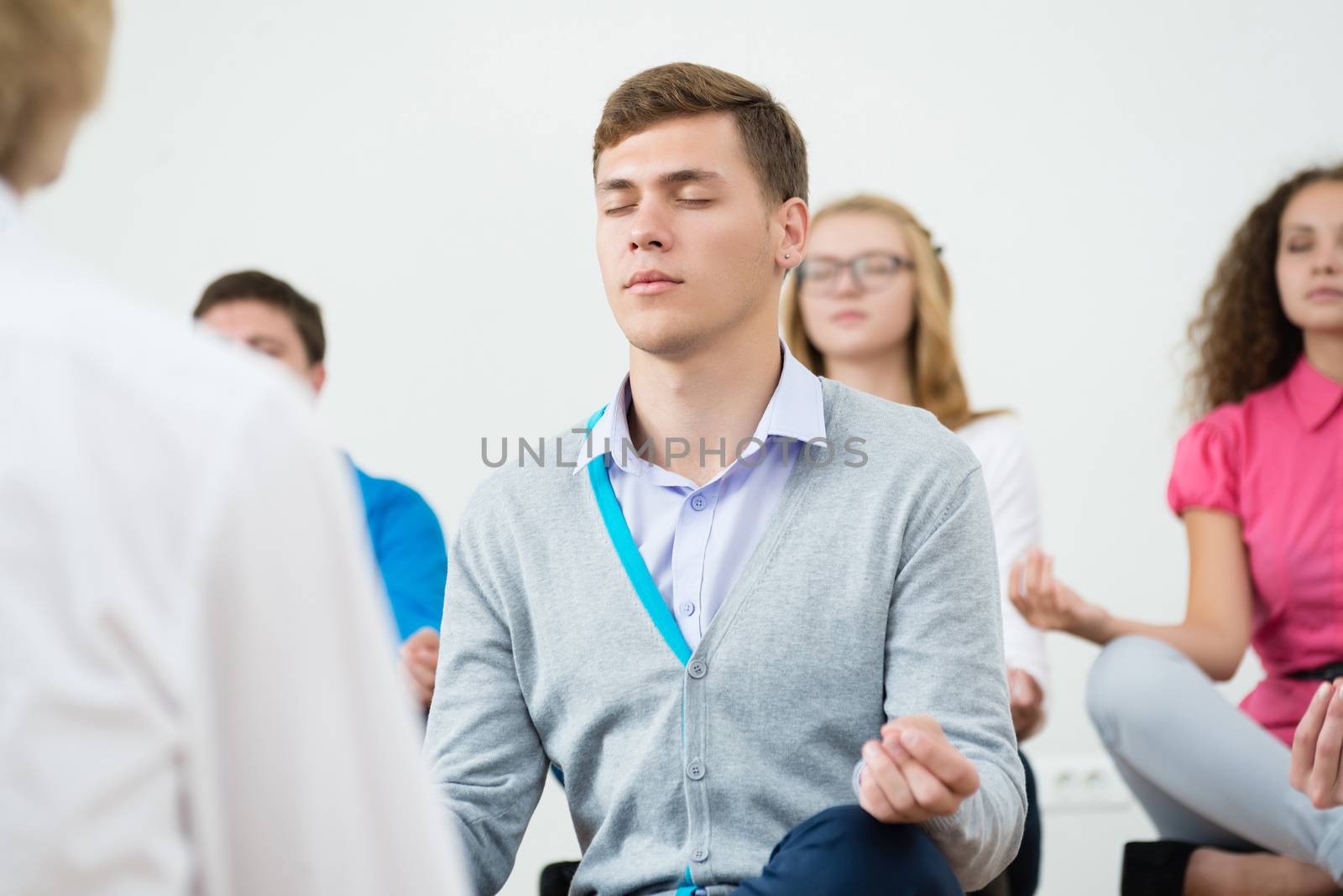 group of young people meditating in office at desk, group meditation