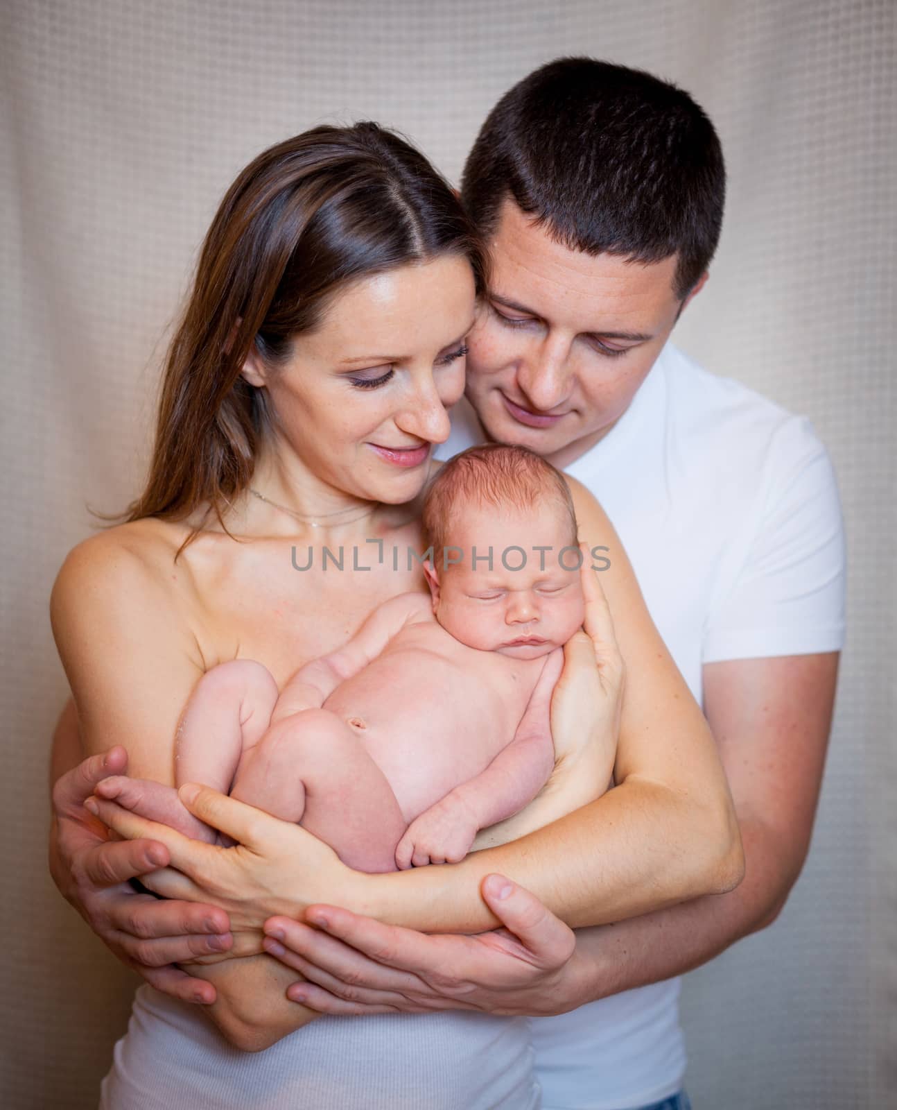 Beautiful mother and father smiling holding their newborn baby boy