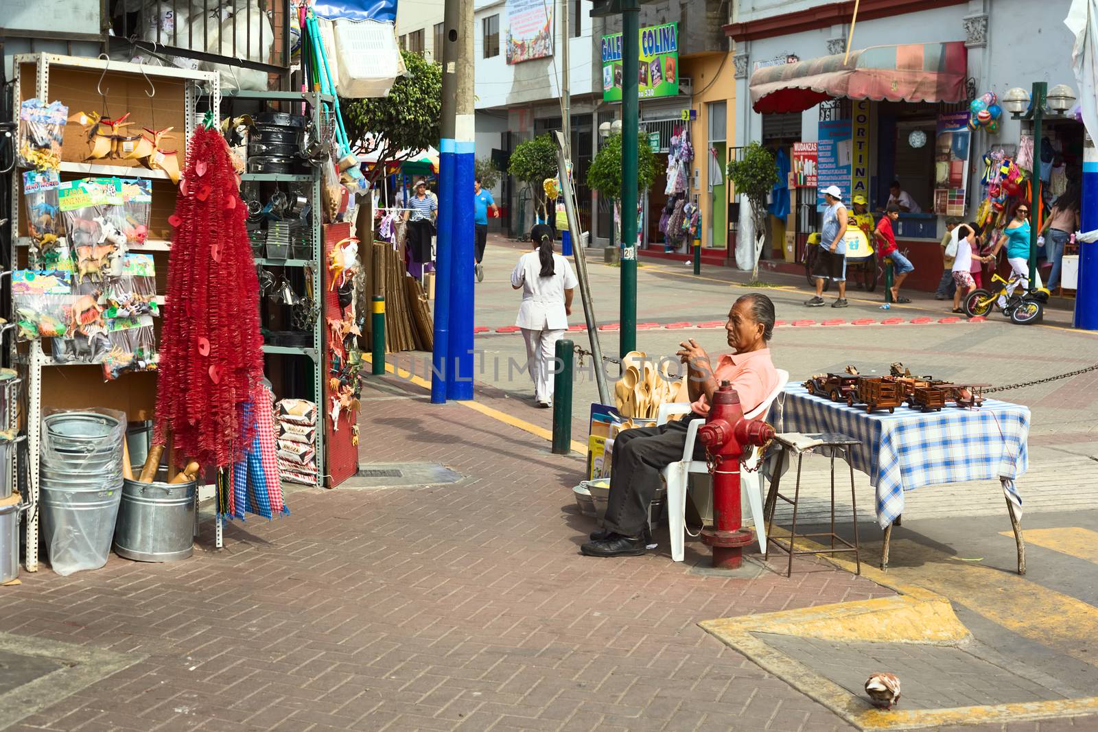 LIMA, PERU - FEBRUARY 13, 2012: Unidentified man selling kitchen utensils and wooden toys at the entrance of the market called Mercado No 1 de Surquillo on February 13, 2012 in Lima, Peru.
