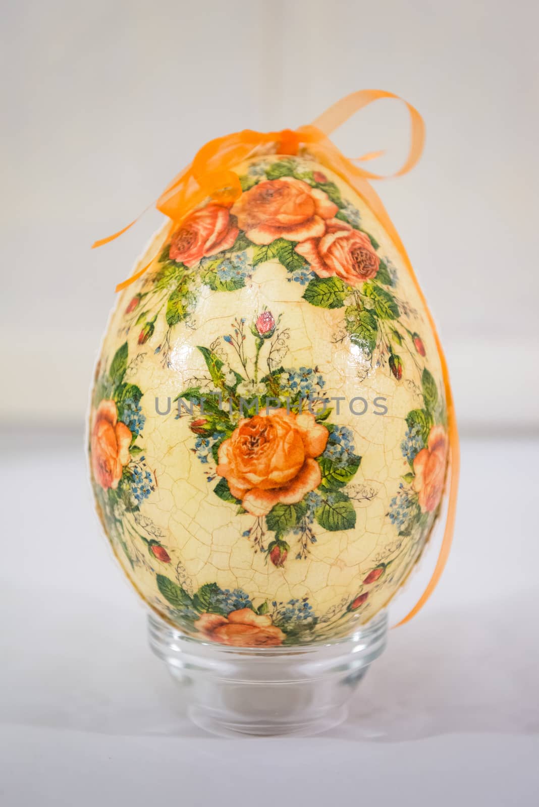 Easter egg decorated with flowers made by decoupage technique on light background