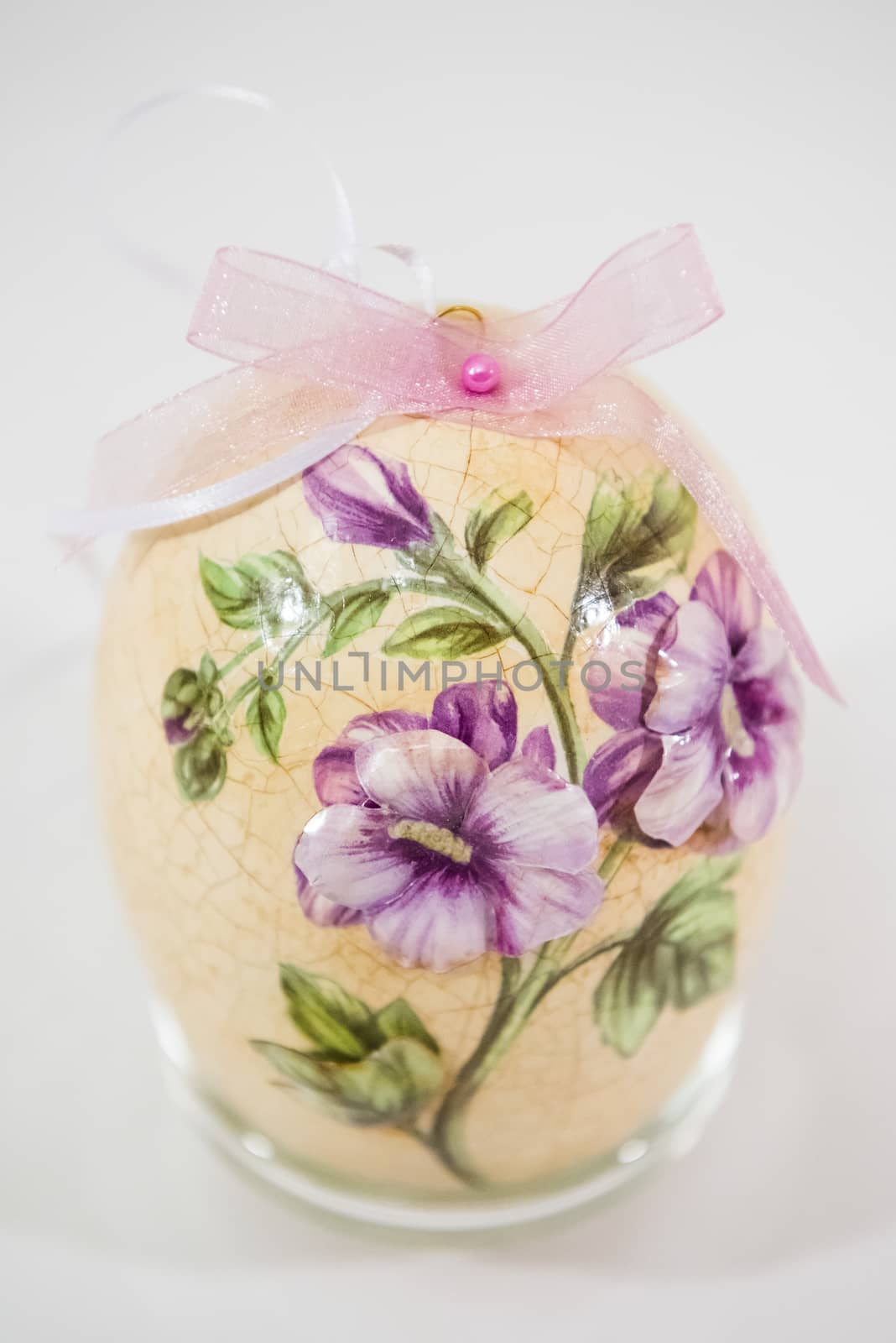 Easter egg decorated with flowers made by decoupage technique on light background