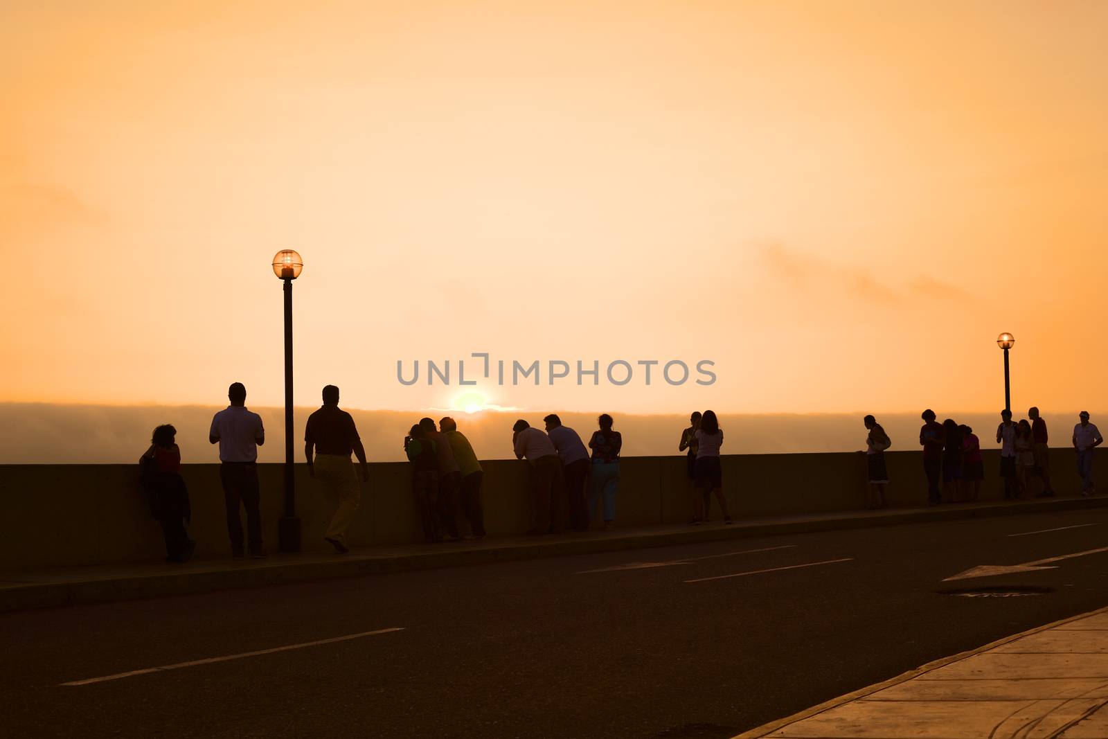 LIMA, PERU - MARCH 11, 2012: Unidentified people watching the sunset over the Pacific ocean from the pavement along the Malecon de la Reserva in Miraflores on March 11, 2012 in Lima, Peru. 