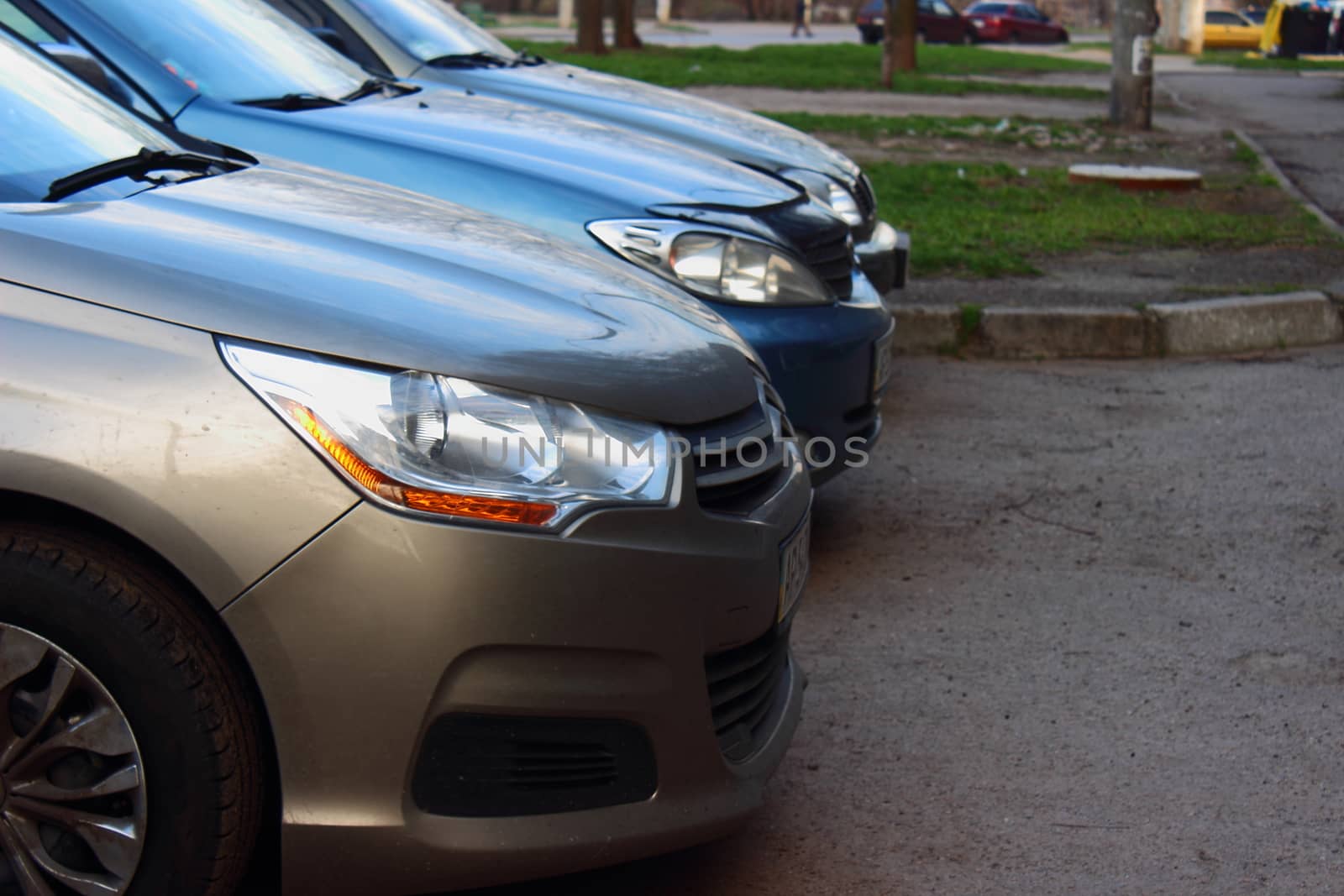 in the parking lot, there are three foreign cars of different colors