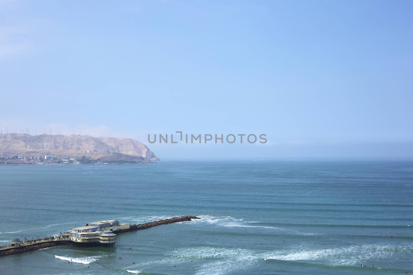 LIMA, PERU - MARCH 24, 2012: View of the restaurant La Rosa Nautica and the coastline of Chorrillos on March 24, 2012 in Lima, Peru. There are many surfers in the water on this sunny summer day.