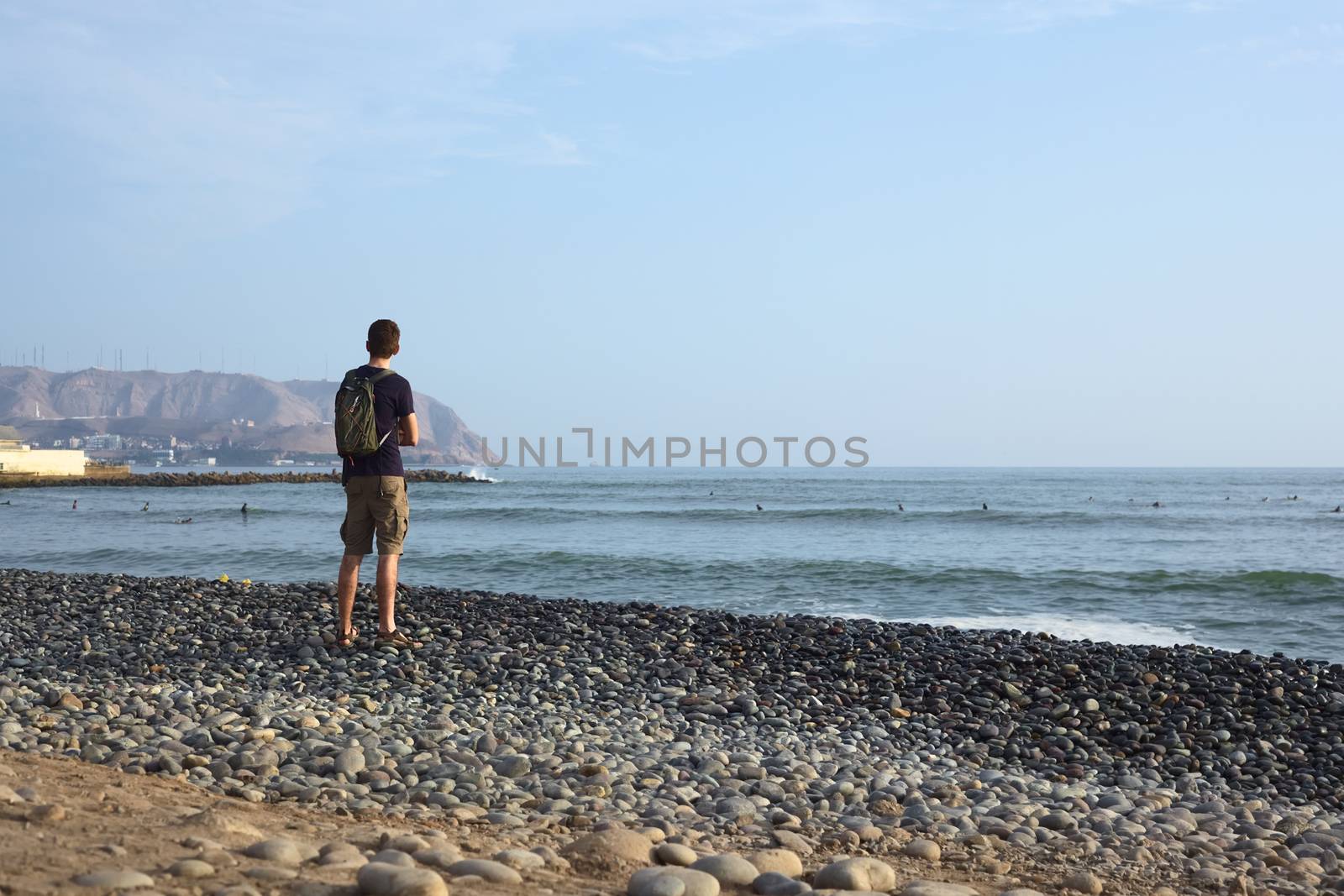 LIMA, PERU - APRIL 2, 2012: Unidentified young man standing on the rocky Pacific coast of Miraflores watching in the direction of the district of Chorrillos on April 2, 2012 in Lima, Peru. 