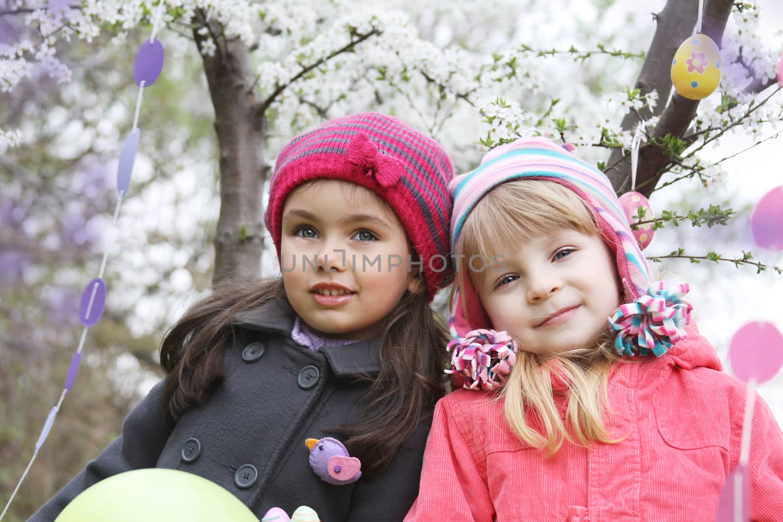 Pretty girls together holding painted egg outdoor in spring