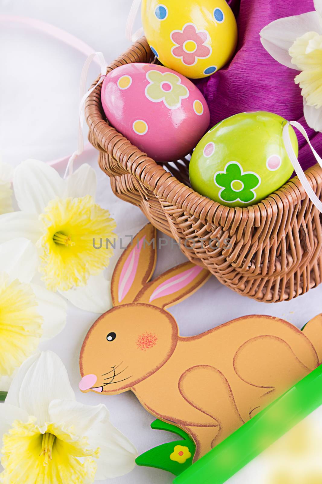 Easter decoration with rabbit, eggs and tulips over white