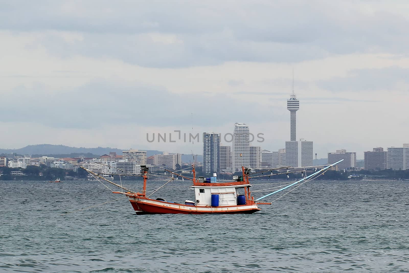 fishing boat in the sea with city view background