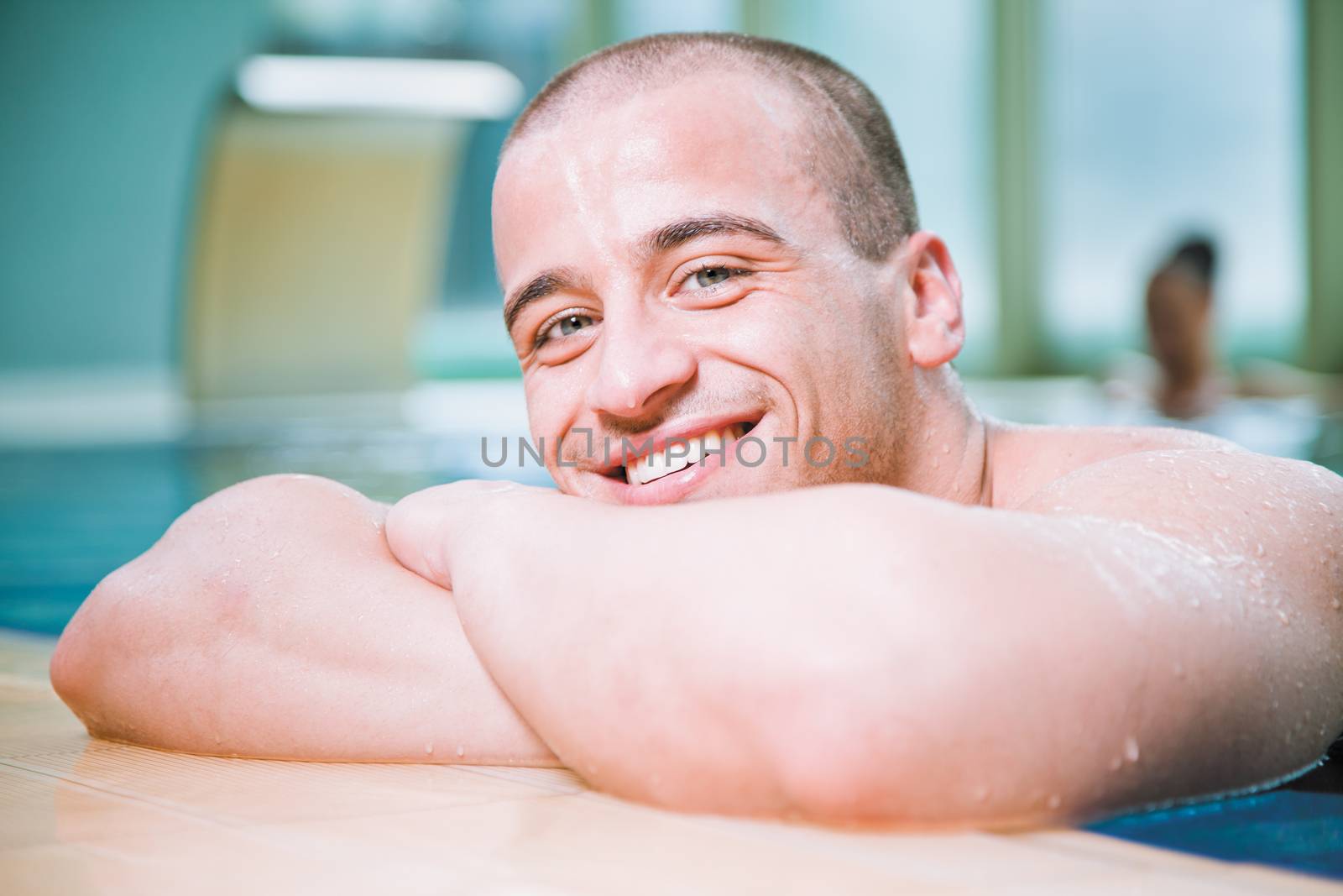 Young attractive male posing with a smile in a swimming pool