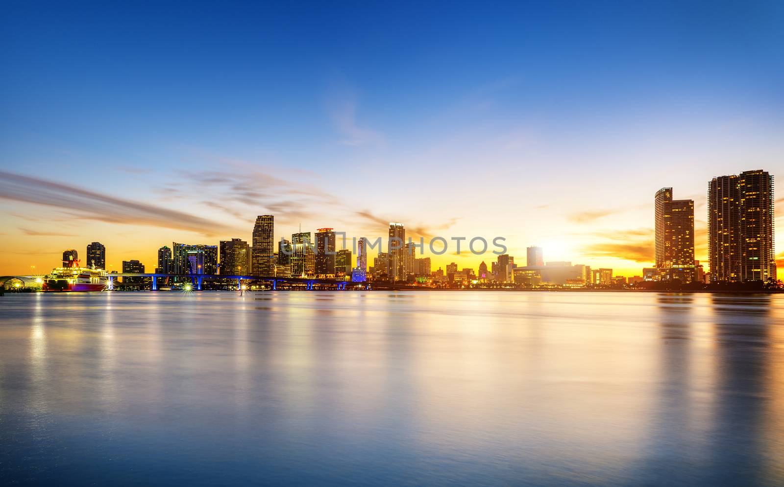 Miami city skyline panorama at dusk with urban skyscrapers over sea with reflection 