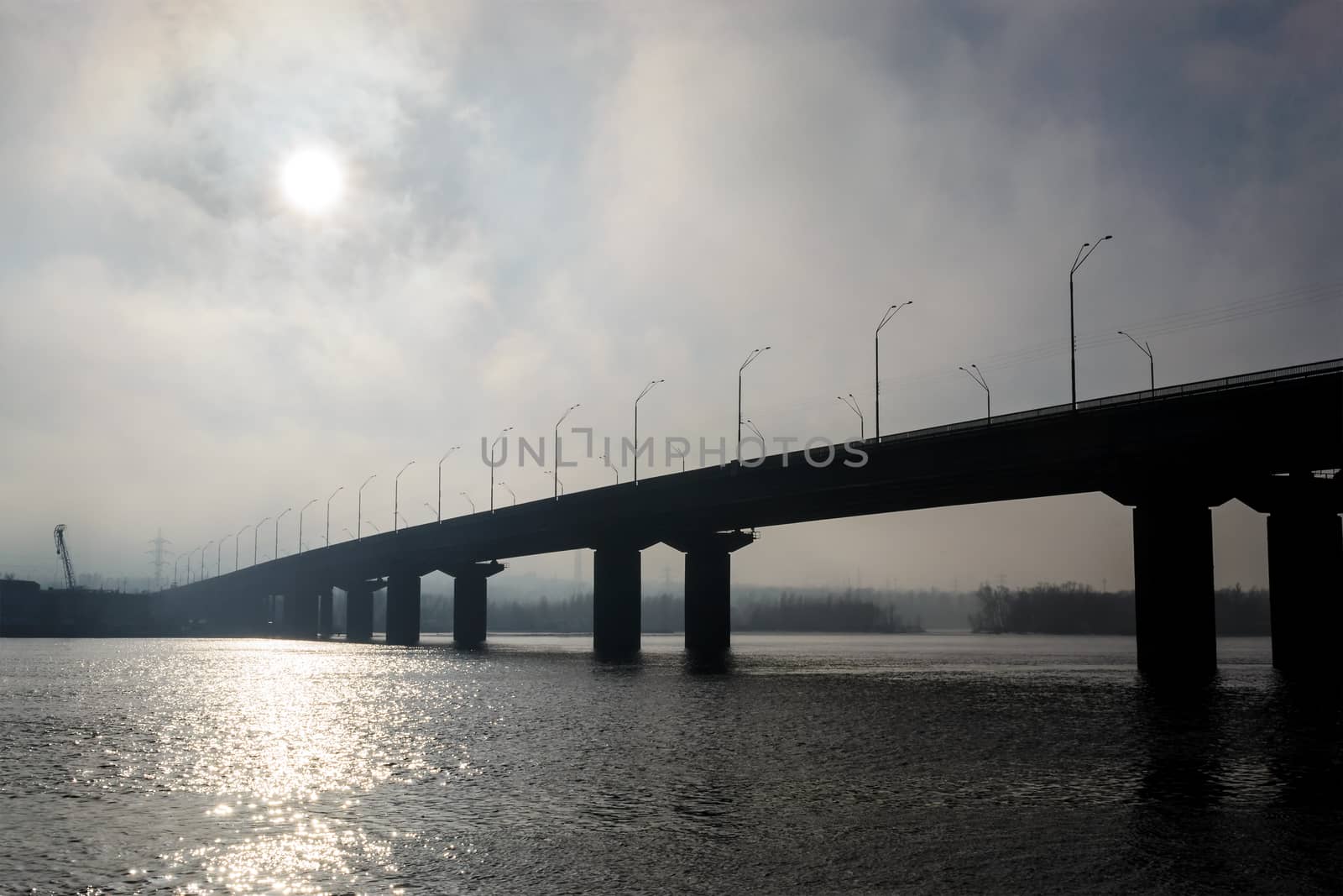 Bridge over a wide river in a fog