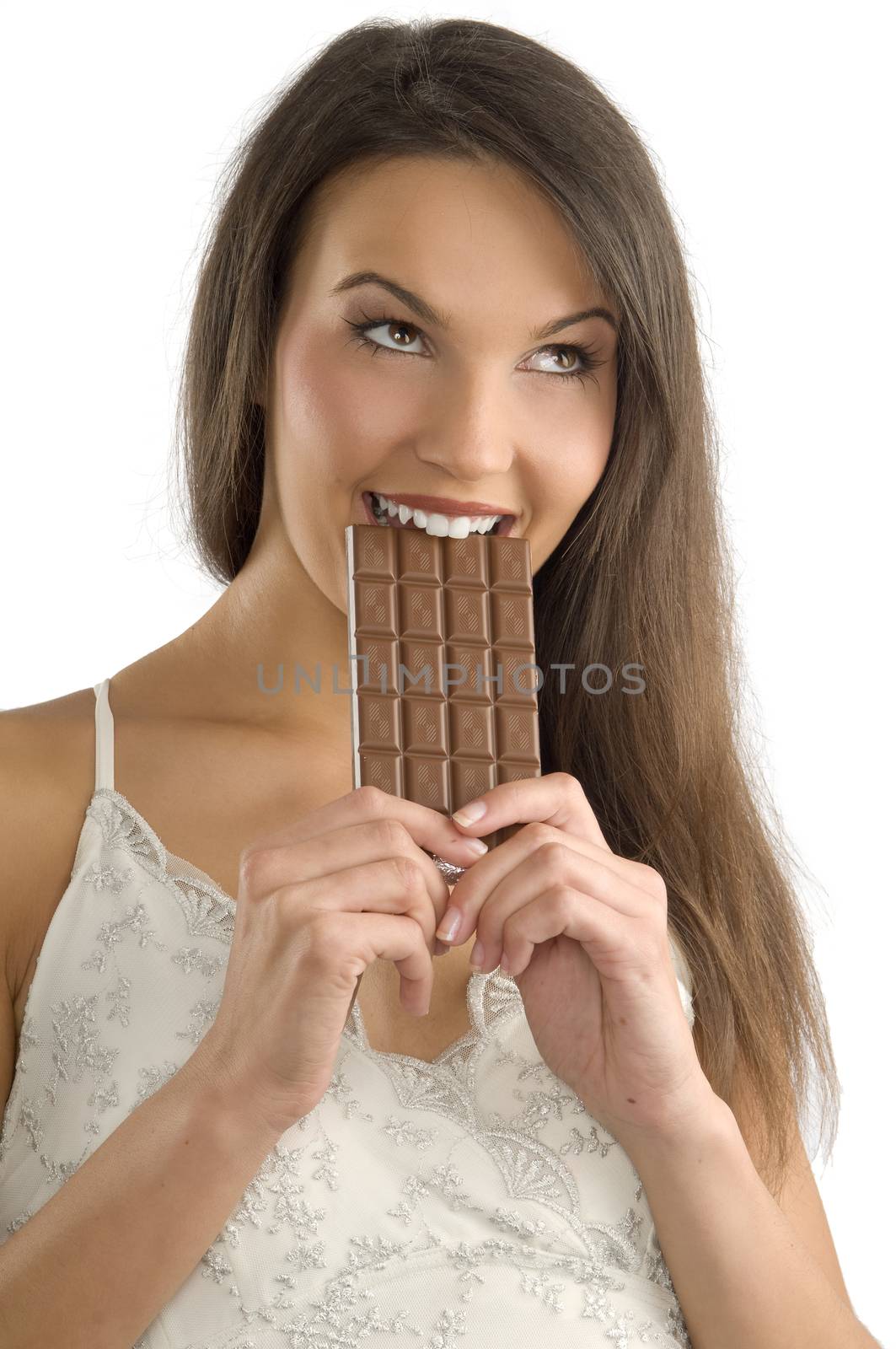 cute young girl bitilng a block of chocolate with her teeth and looking up with eyes