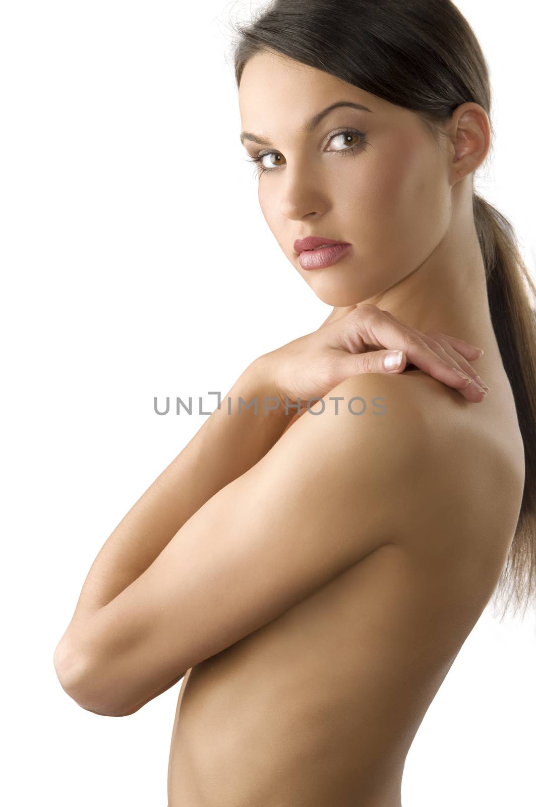 pretty girl with with ponytail and hands on her nude shoulder looking in camera