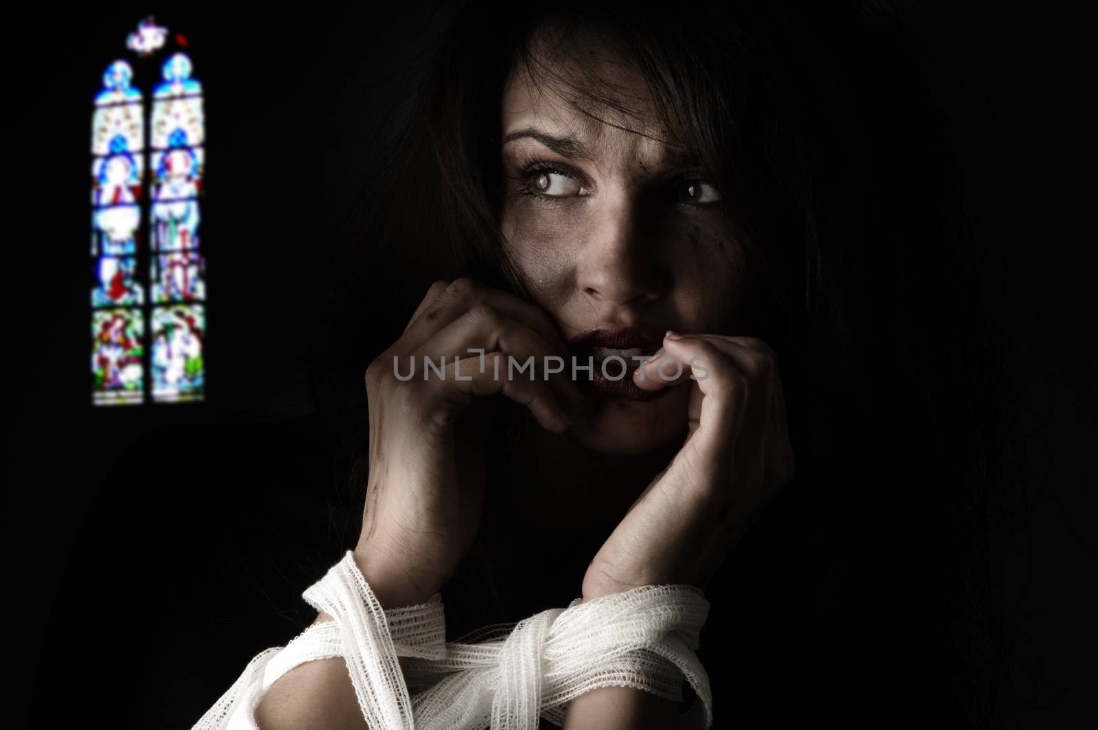 woman in fear with patch around her arms an a church windows on back