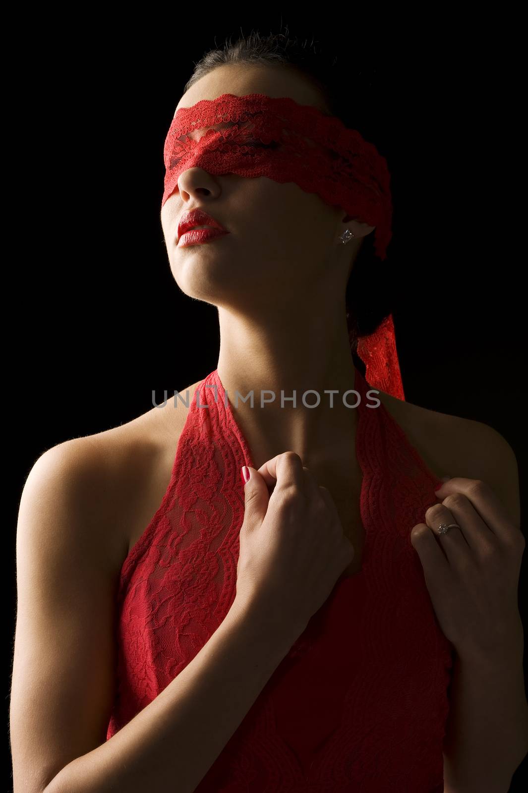 sensual portrait of a young brunette on black background with a red mask of lace