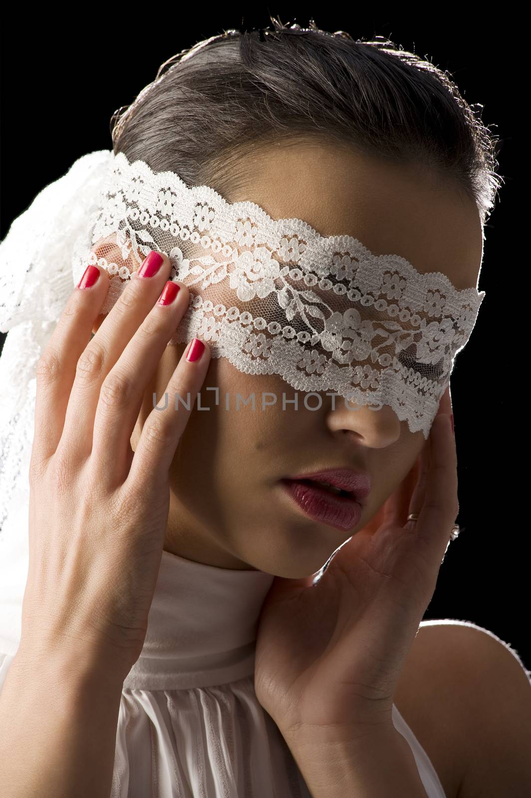 pretty young woman with dark hair wearing a white shirt and a white lace mask on black background