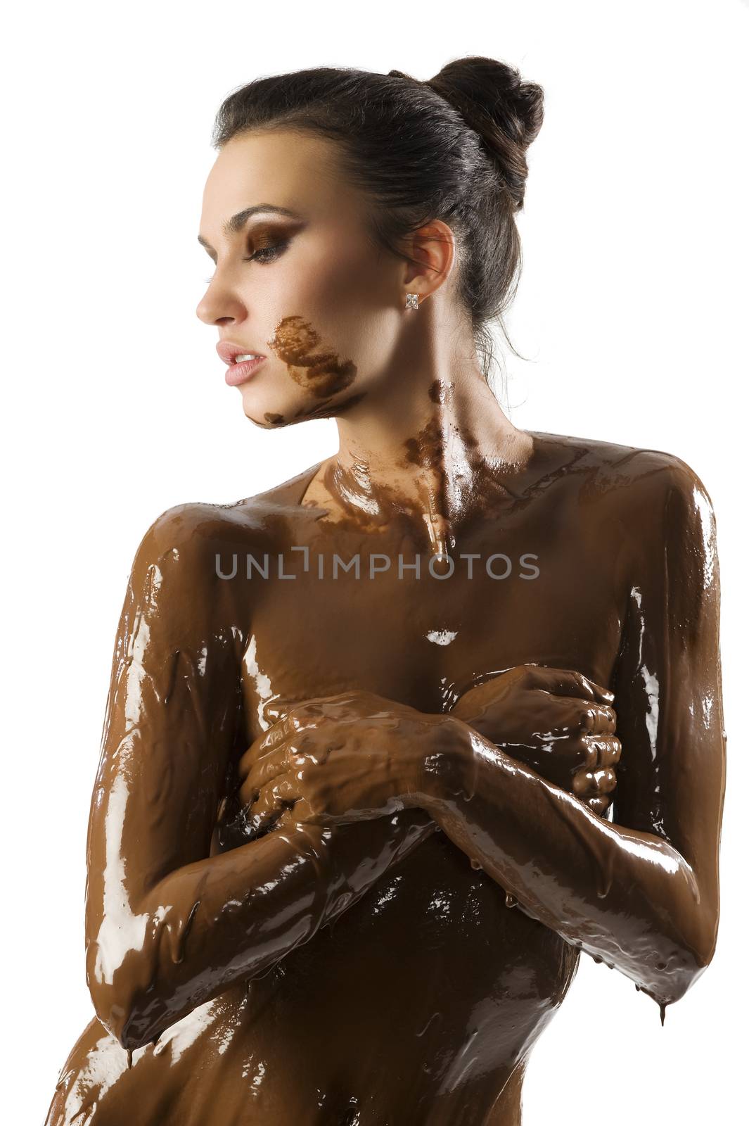 amazing shot of a young beautiful brunette with her naked body covered of sweet cream chocolate