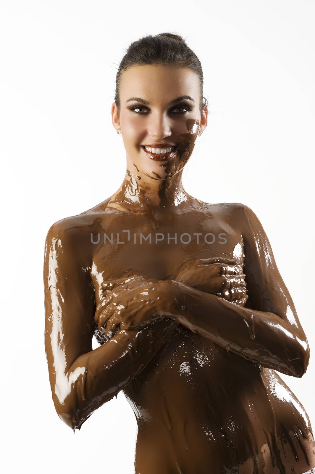 amazing shot of a young beautiful brunette with her naked body covered of sweet cream chocolate