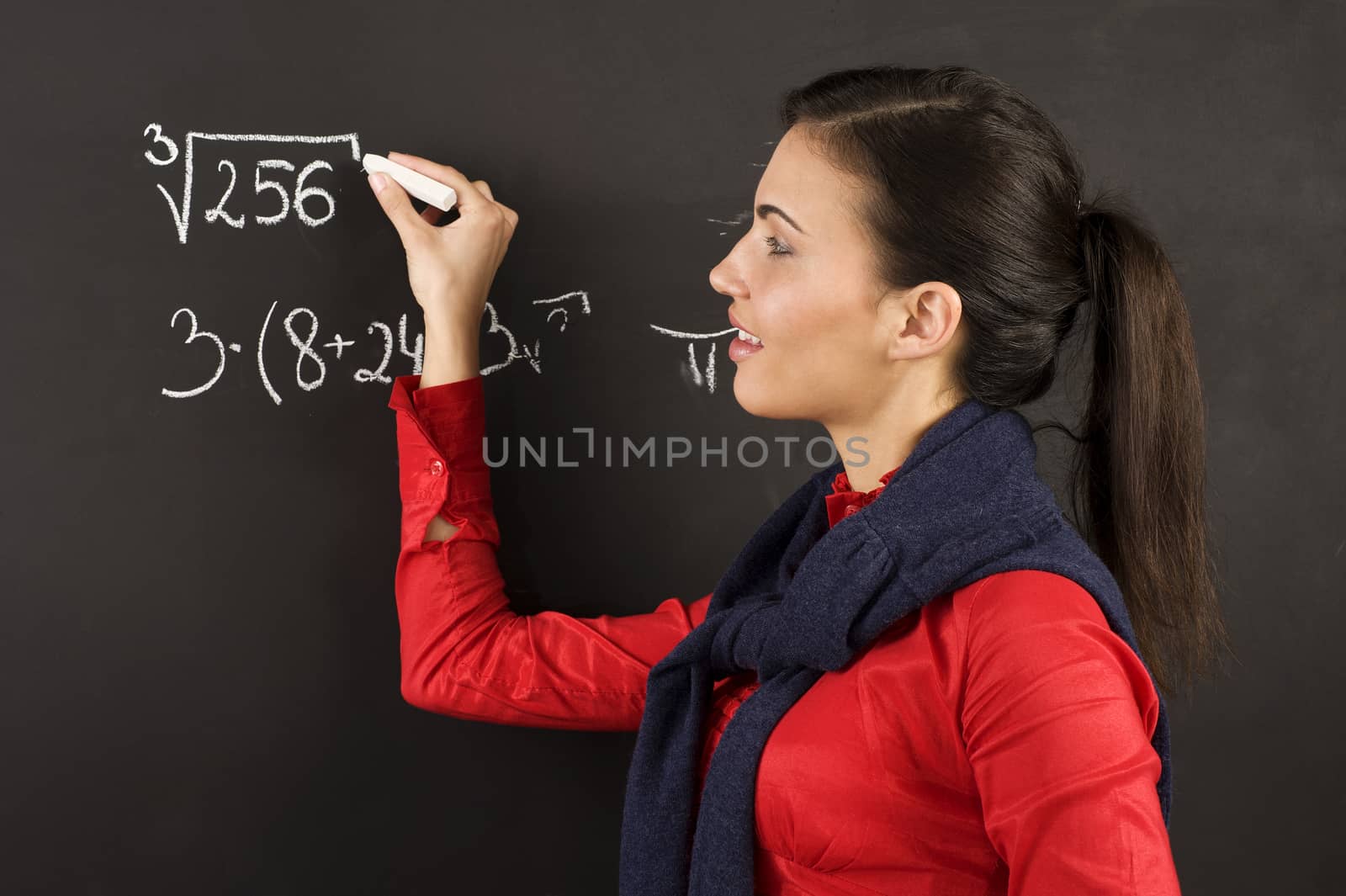 pretty young college student writing on the chalkboard/blackboard during a math class