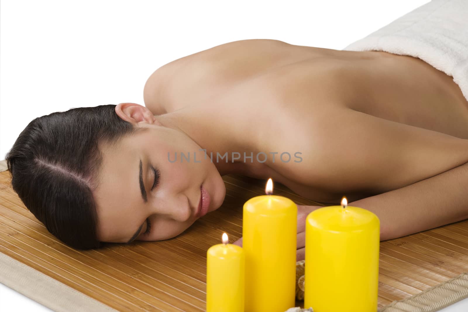 attractive beautiful caucasian woman lying down on a massage bed at a spa with candle