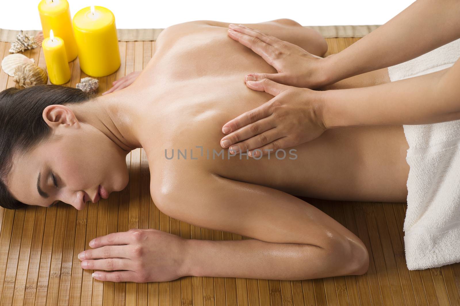 cute woman laying down on wood carpet with candle near getting an oil massage
