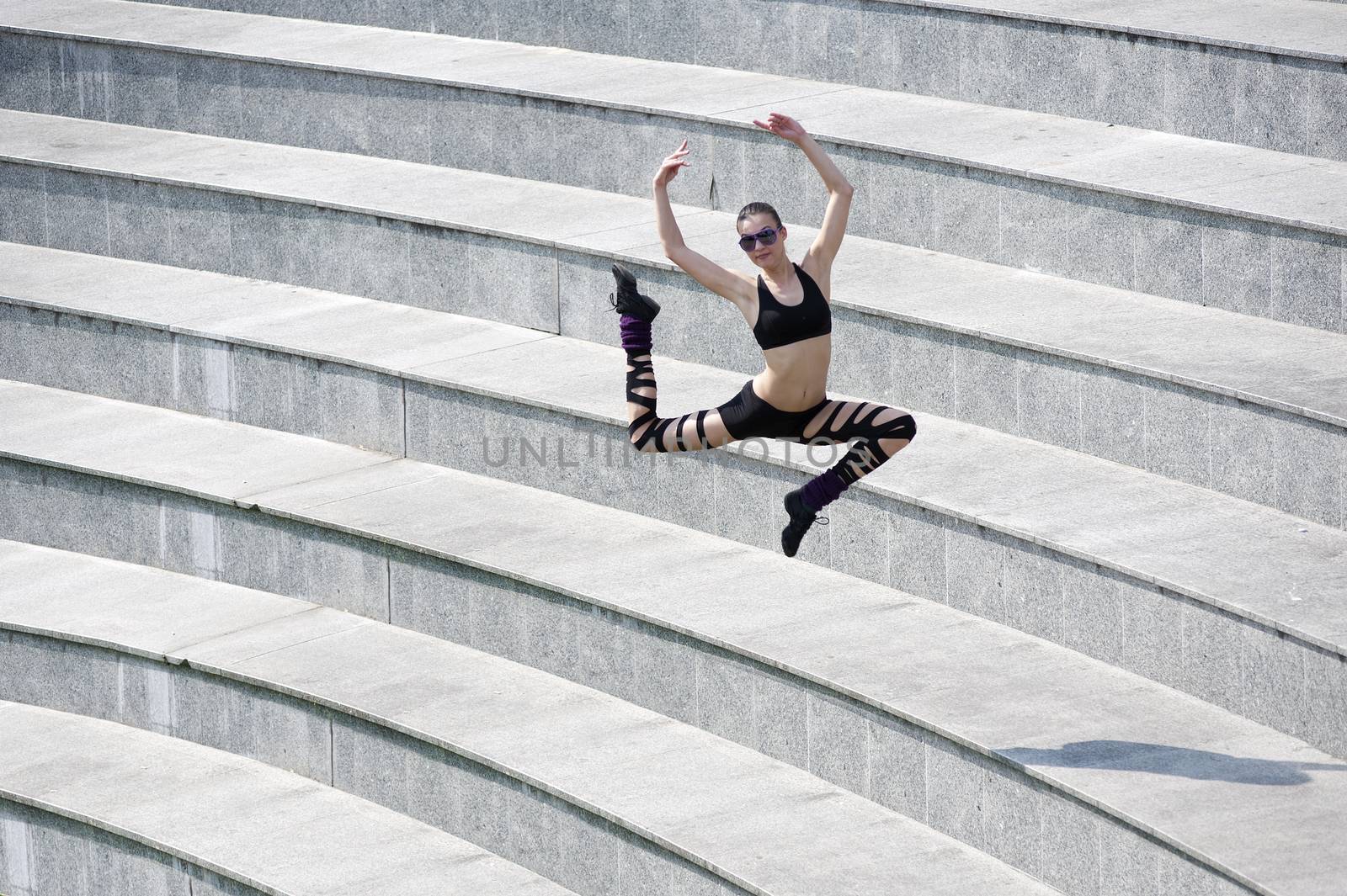 young cute dancer woman jumping outside in urban arena theater