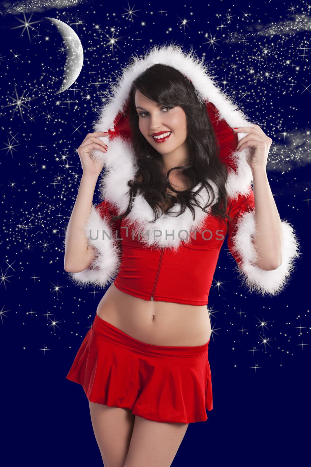 pretty brunette wearing a red santa claus dress with hood and white fur over christmas night star background